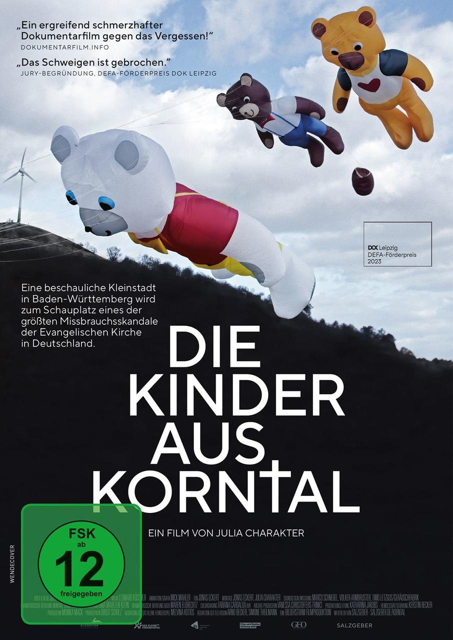 Drei Teddybär-Luftballons steigen in den Himmel, über einer Landschaft mit Windrad.