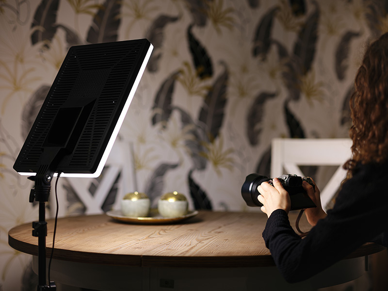 Osoba fotografująca panel świetlny na stole z ozdobnymi kulami.