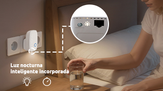 Una luz nocturna con enchufe y un vaso de agua en una mesita de noche.