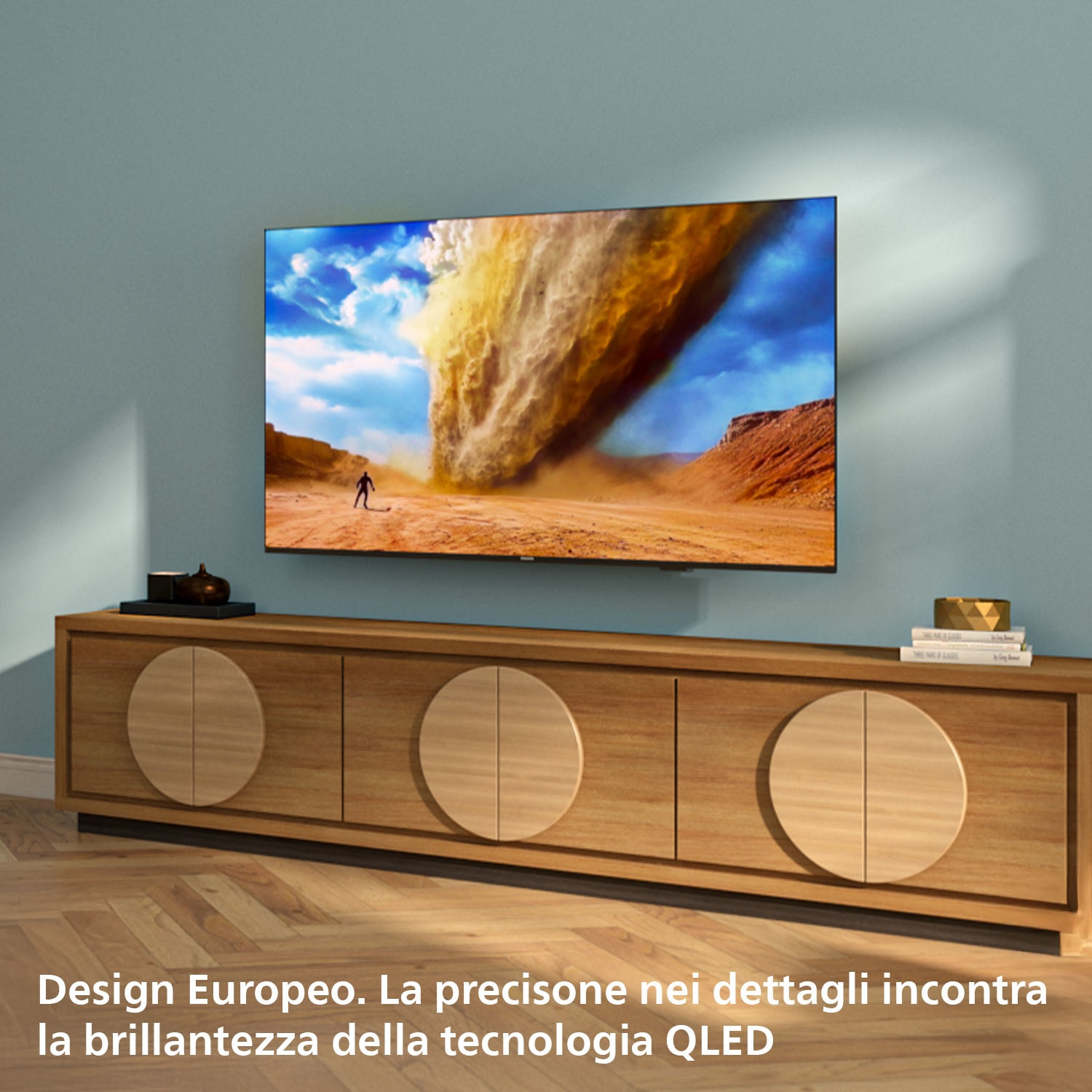 Un televisore mostra una tempesta di polvere nel deserto sopra un mobile in legno.