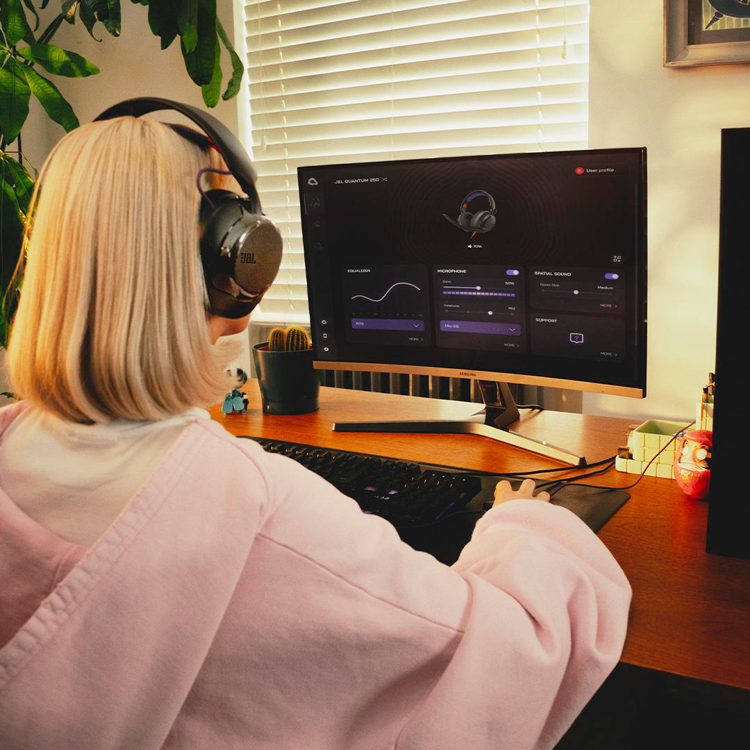 Eine Person mit Kopfhörern sitzt vor einem Computer und konfiguriert Audioeinstellungen.