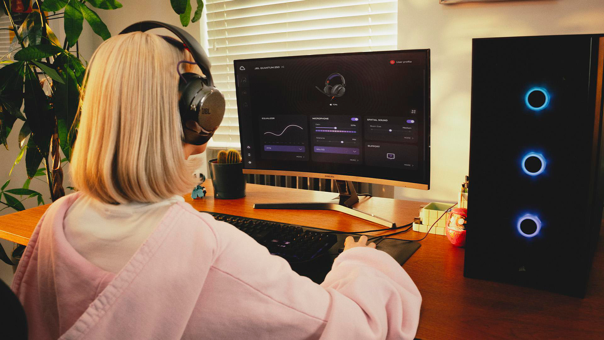 Person mit Kopfhörern am Schreibtisch, der auf einen Monitor mit Spieleinstellungen blickt.