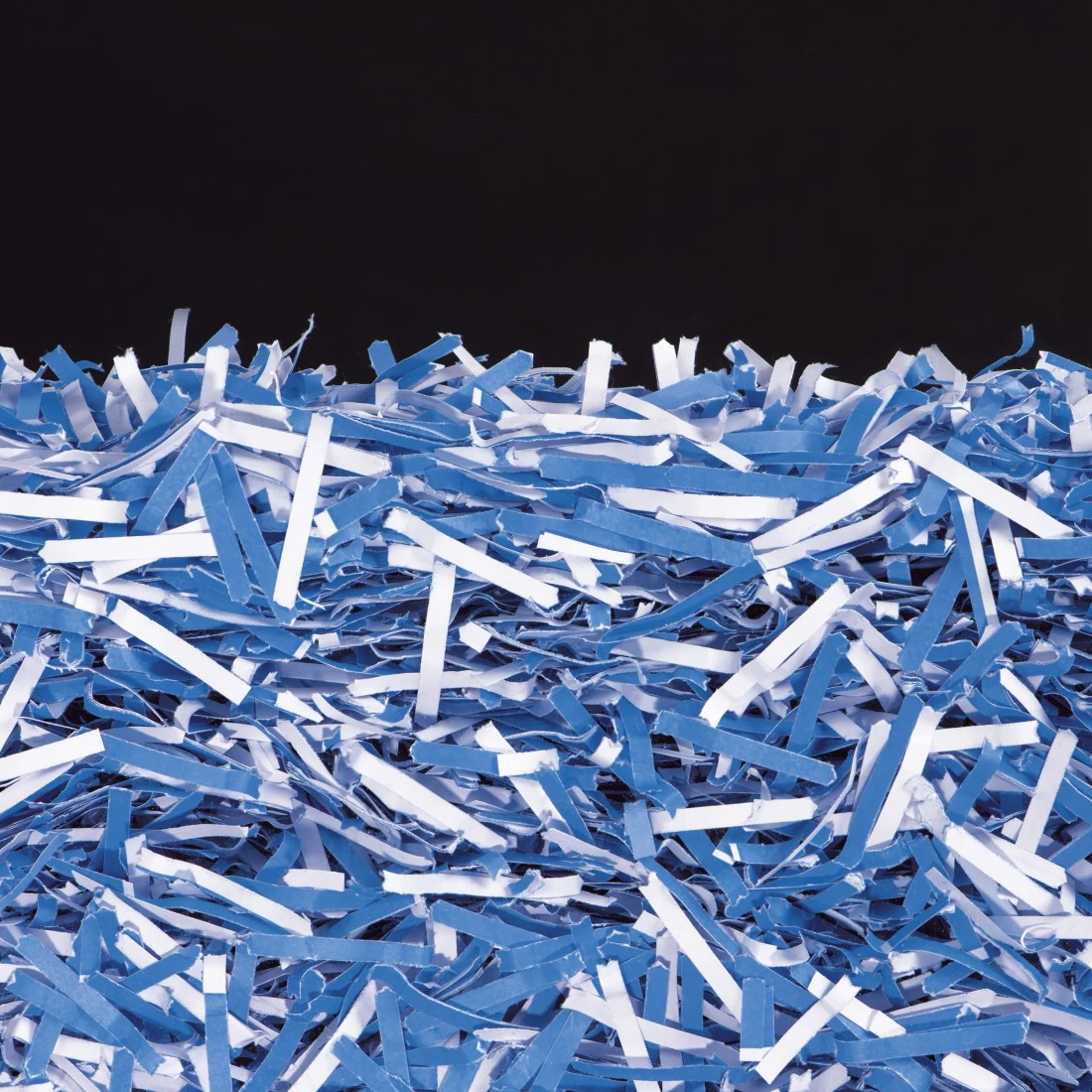Blau-weißer Papierschnipselberg vor schwarzem Hintergrund.