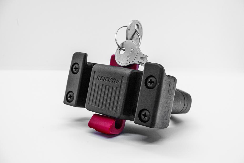 Ein schwarzer Klickfix-Adapter mit Schlüssel auf weißem Hintergrund.