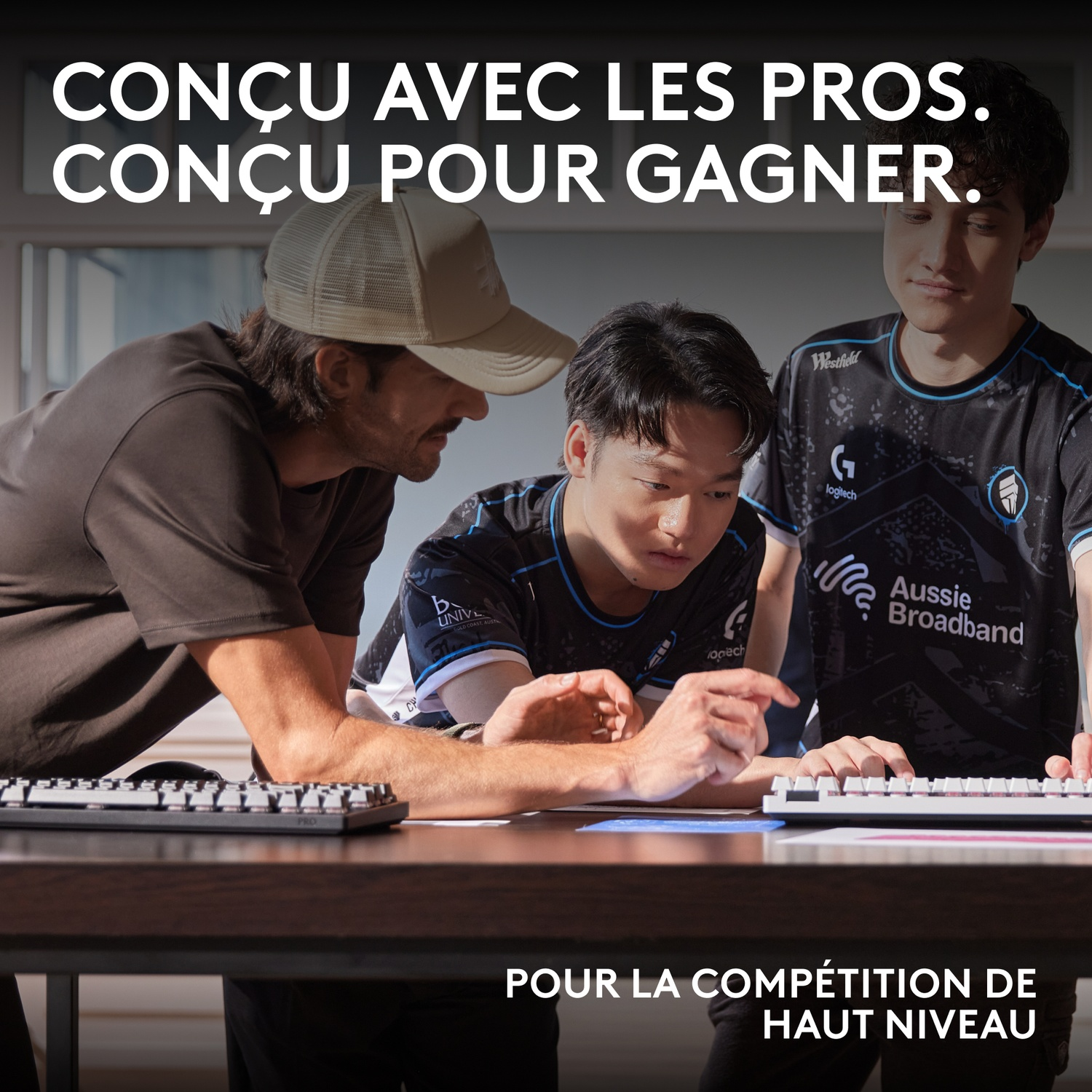 Trois hommes en maillot regardent des claviers d'ordinateur.