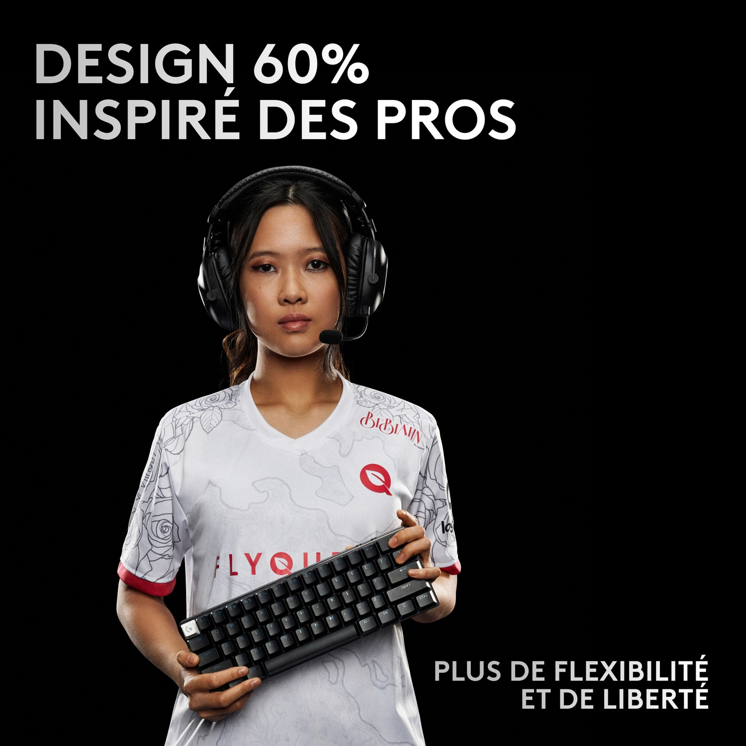 Une femme portant un casque tient un clavier. Elle porte une chemise blanche.