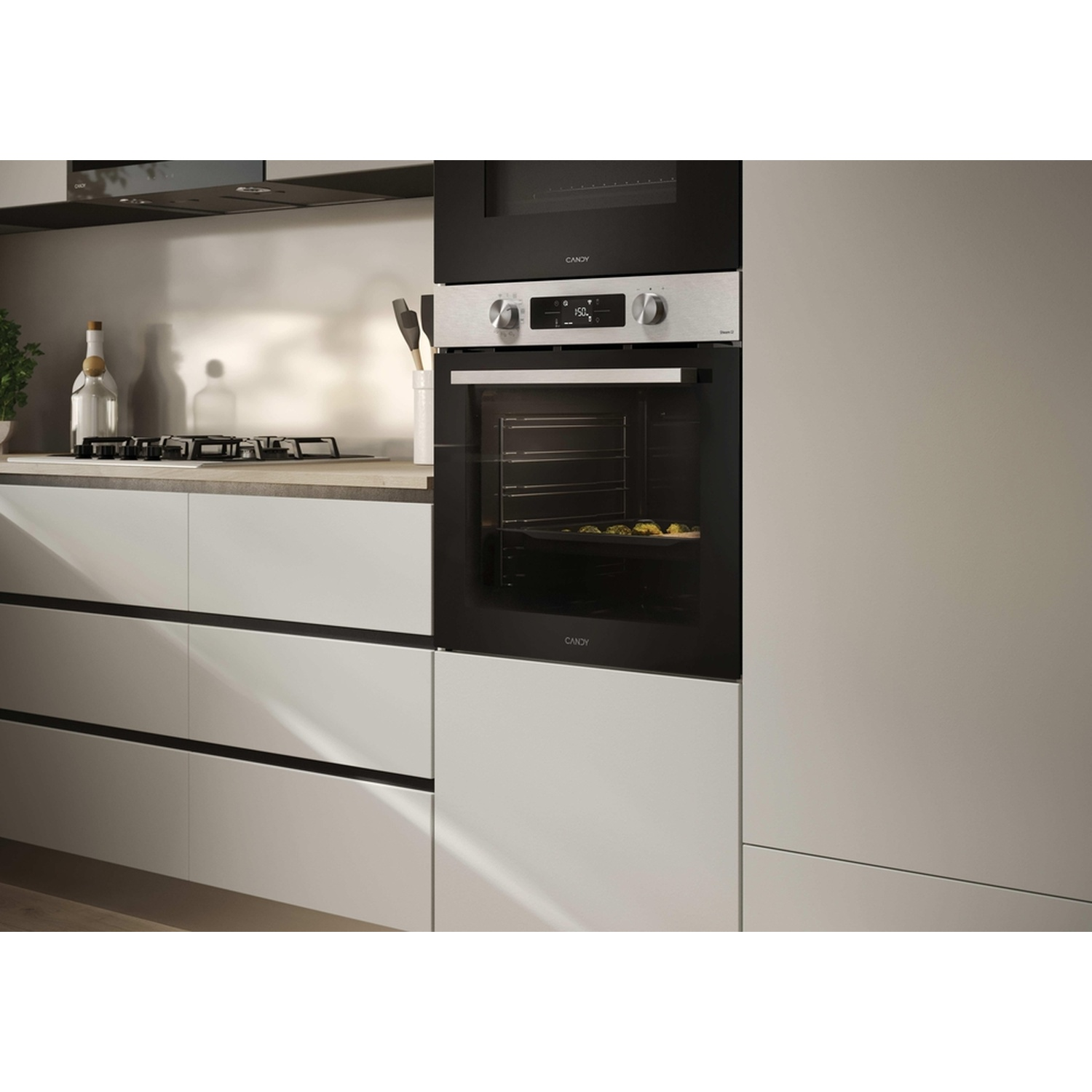 Forno da incasso moderno con pannello argento e display digitale, accanto a un piano di lavoro con piano cottura a gas.