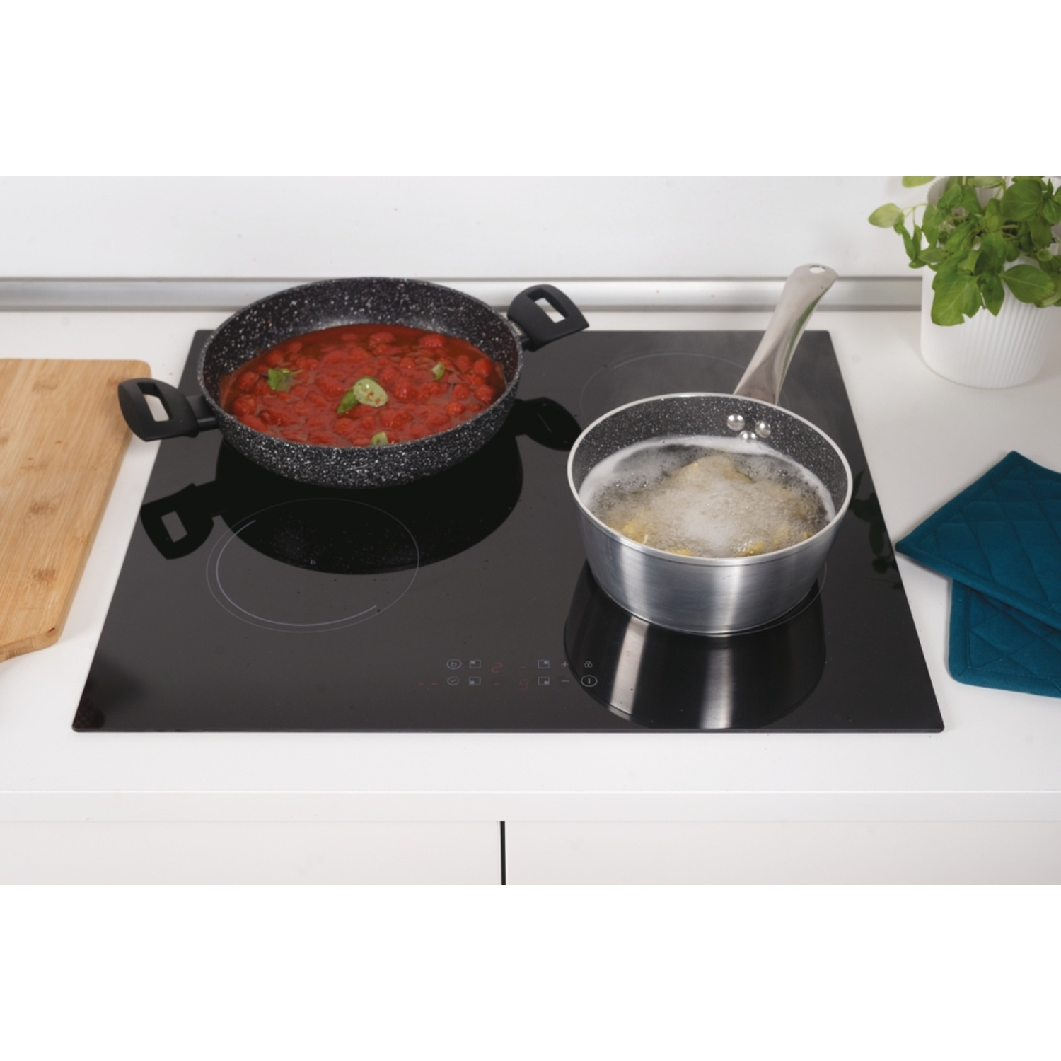 Un piano cottura a induzione nero con una pentola di sugo e una pentola di pasta bollente.