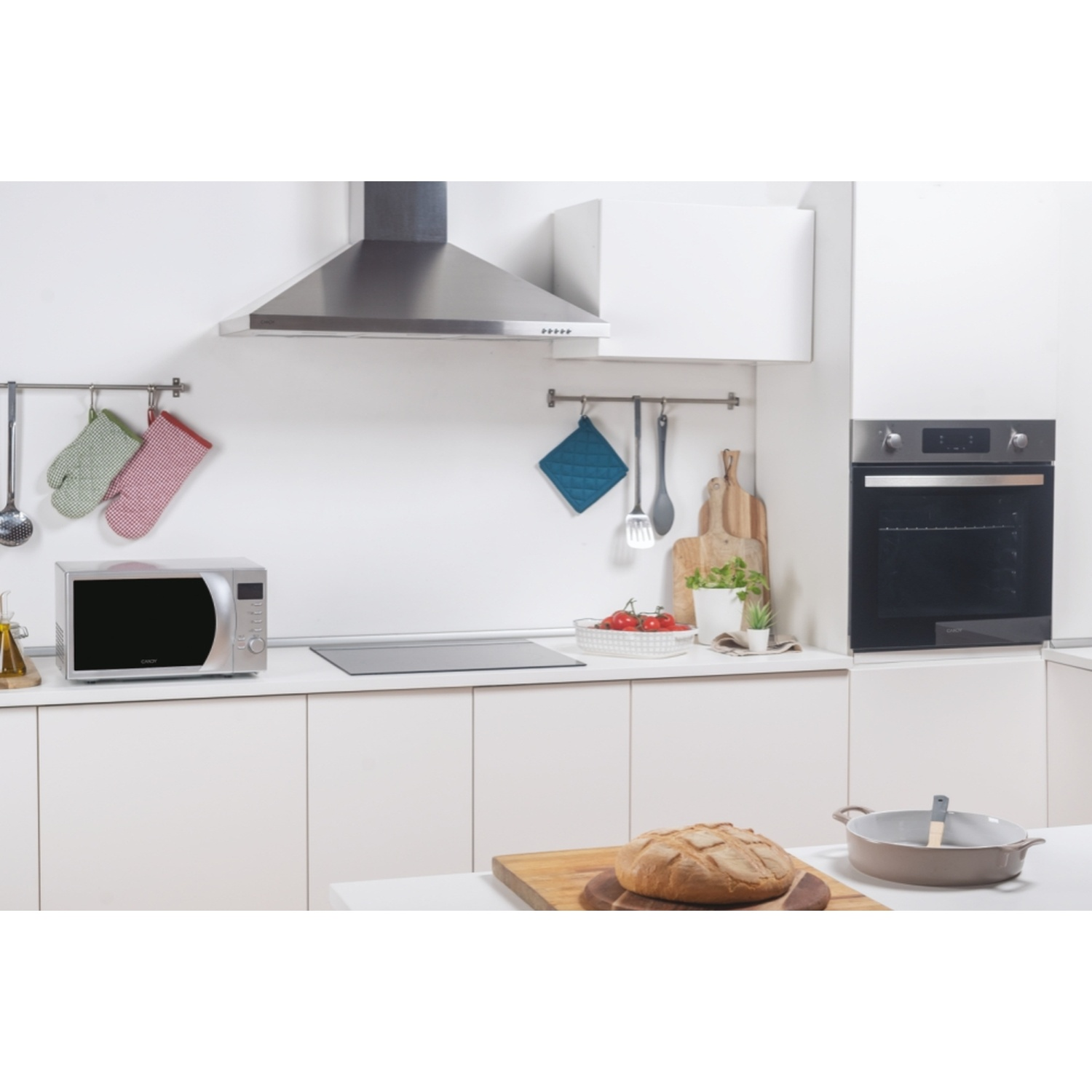 Cucina moderna con microonde, forno, cappa e pane.