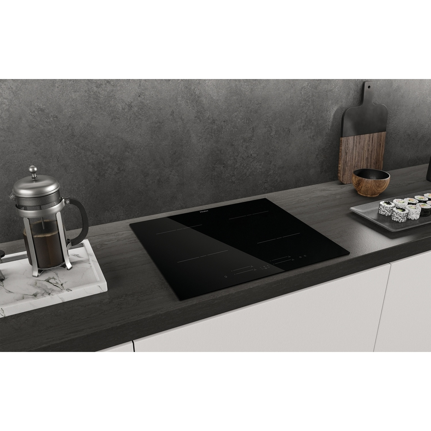 Un piano cottura a induzione nero con caffettiera French press e sushi.