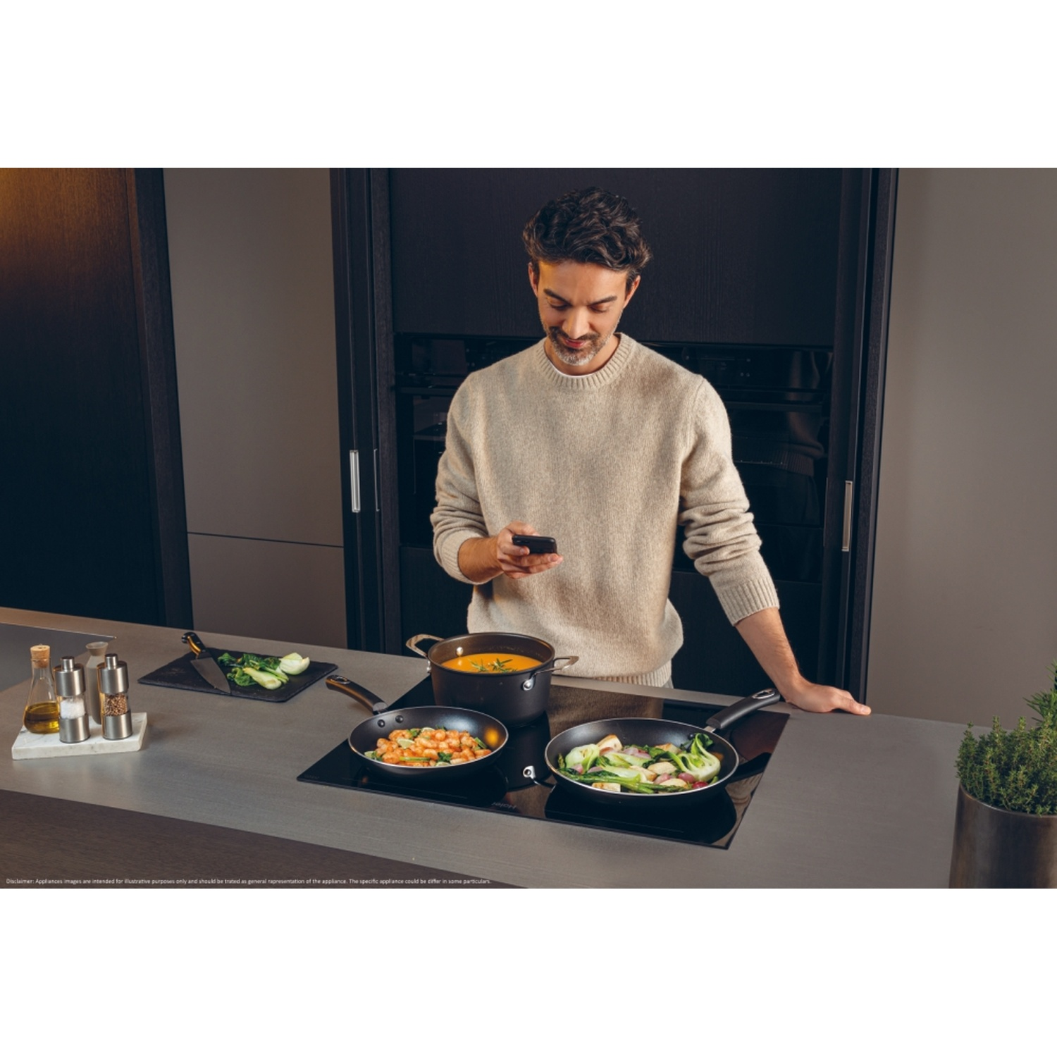 Uomo cucina con telefono in cucina. Due padelle sui fornelli.