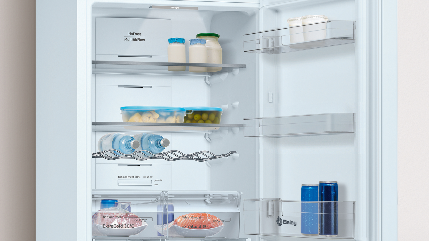 Un refrigerador abierto con frascos, botellas, latas y carne envasada.