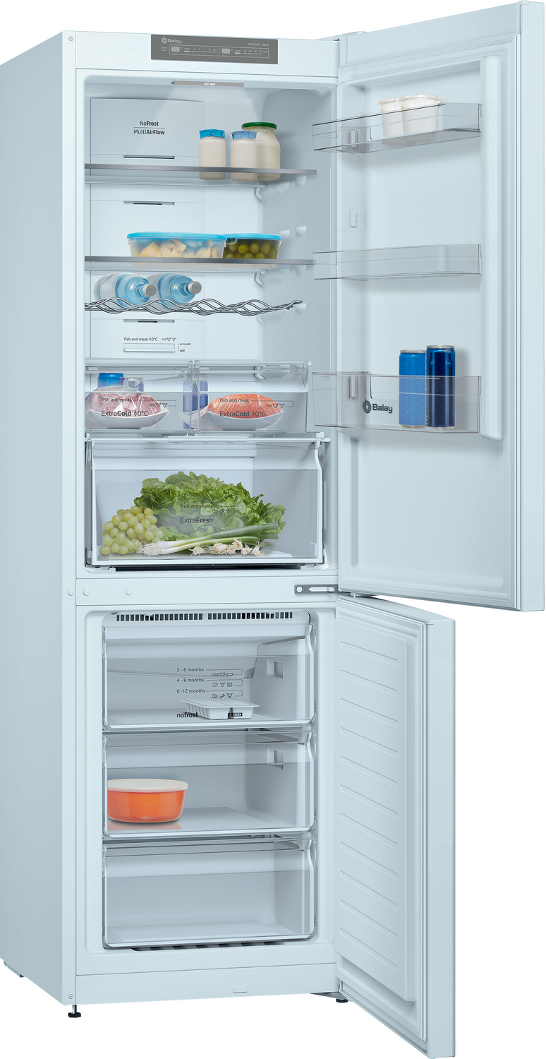 Refrigerador blanco abierto con comida: verduras, uvas, botellas y tarros.