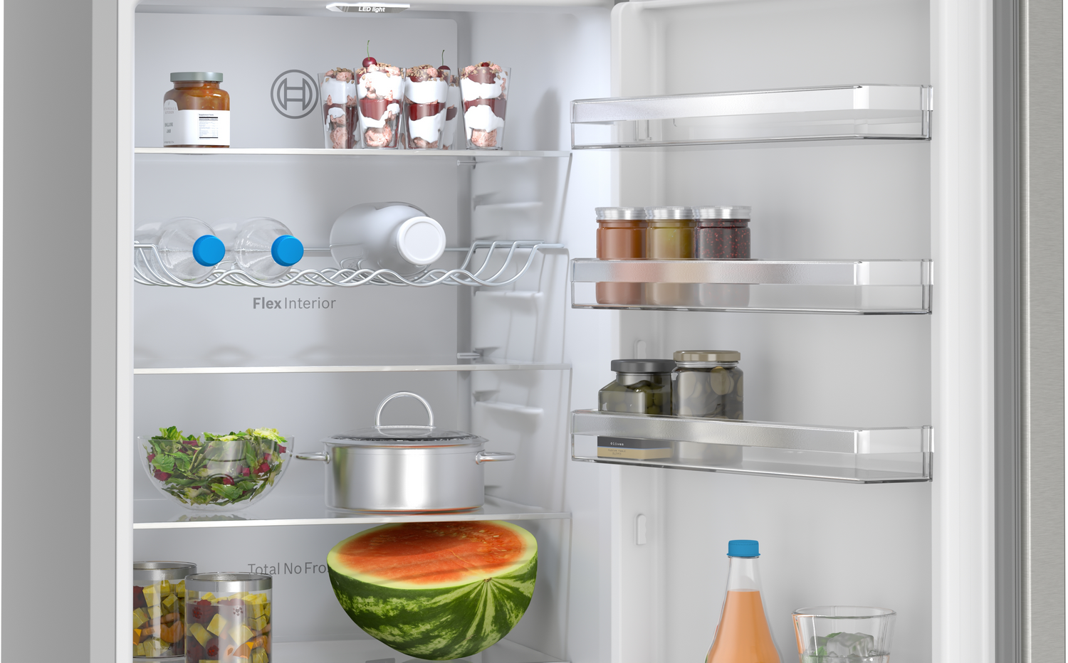 Interior de refrigerador con frascos, botellas, bayas, ensalada, olla, melón y vasos.
