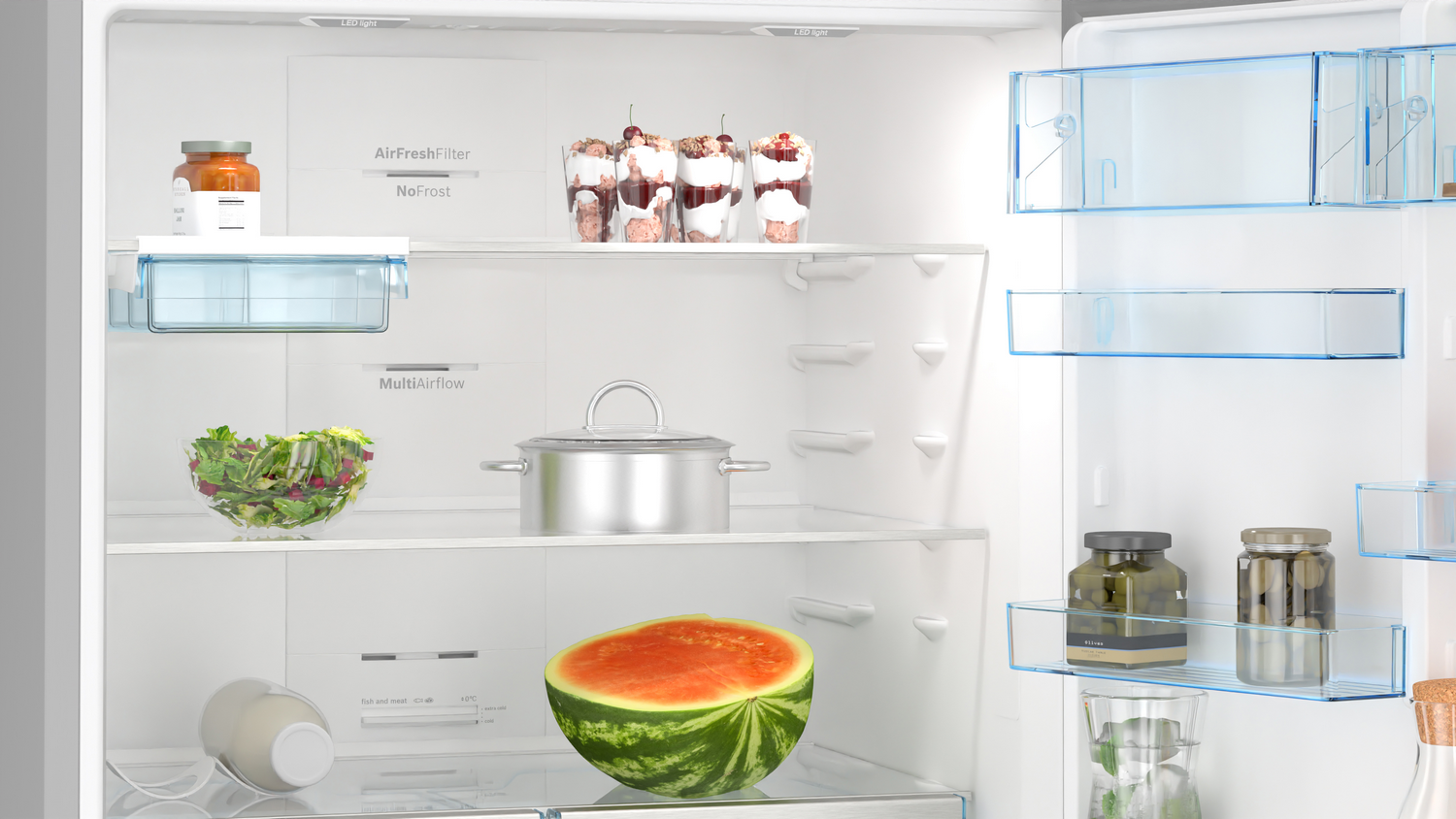 Un refrigerador abierto con vasos, ensalada, olla, sandía y frascos.