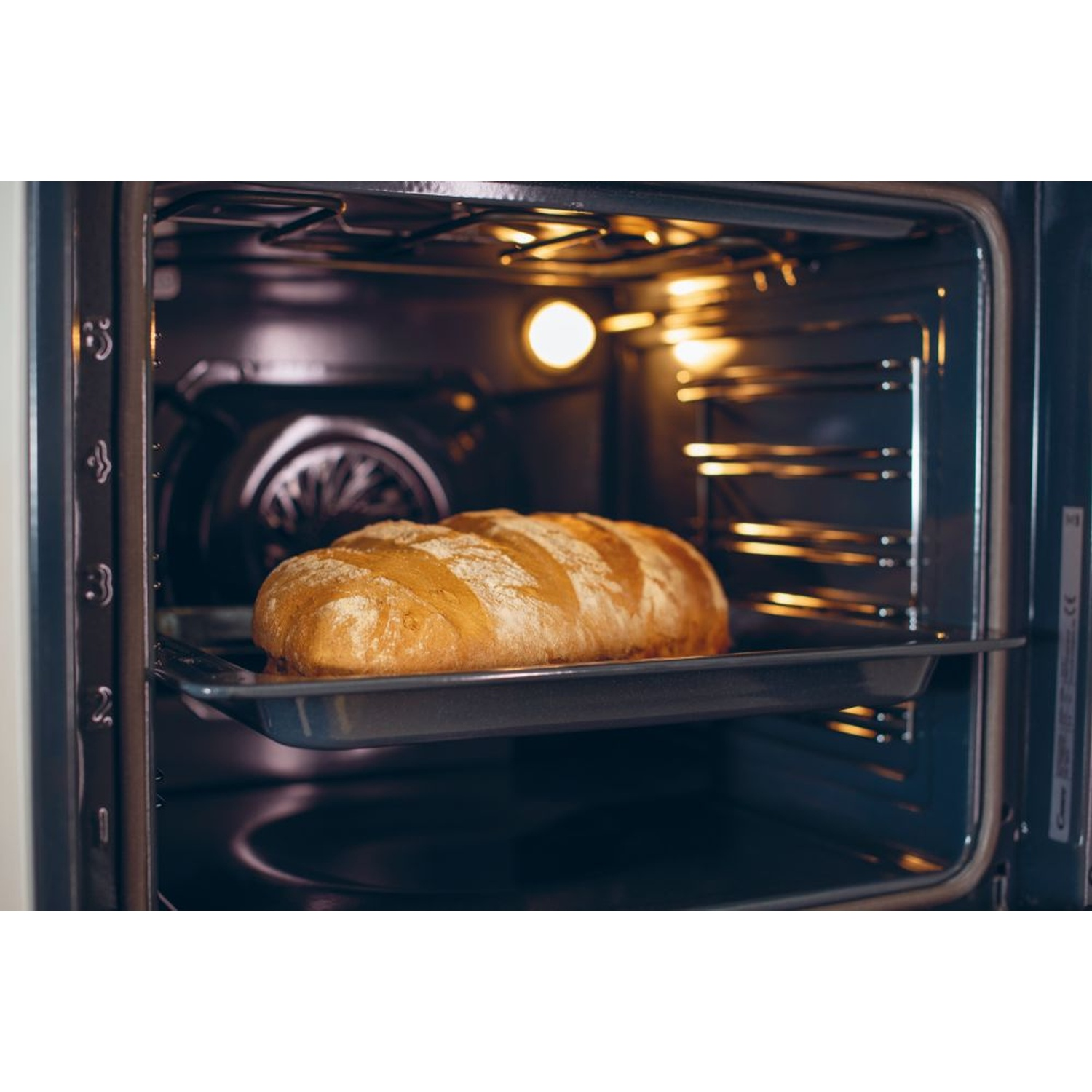 Una pagnotta dorata riposa su una teglia all'interno di un forno illuminato.