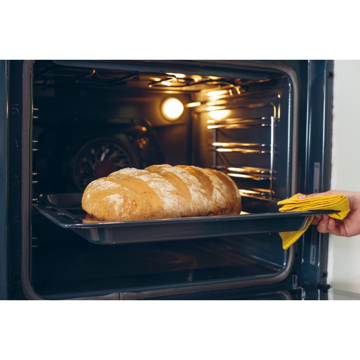 Una pagnotta su una teglia viene tolta da un forno caldo.