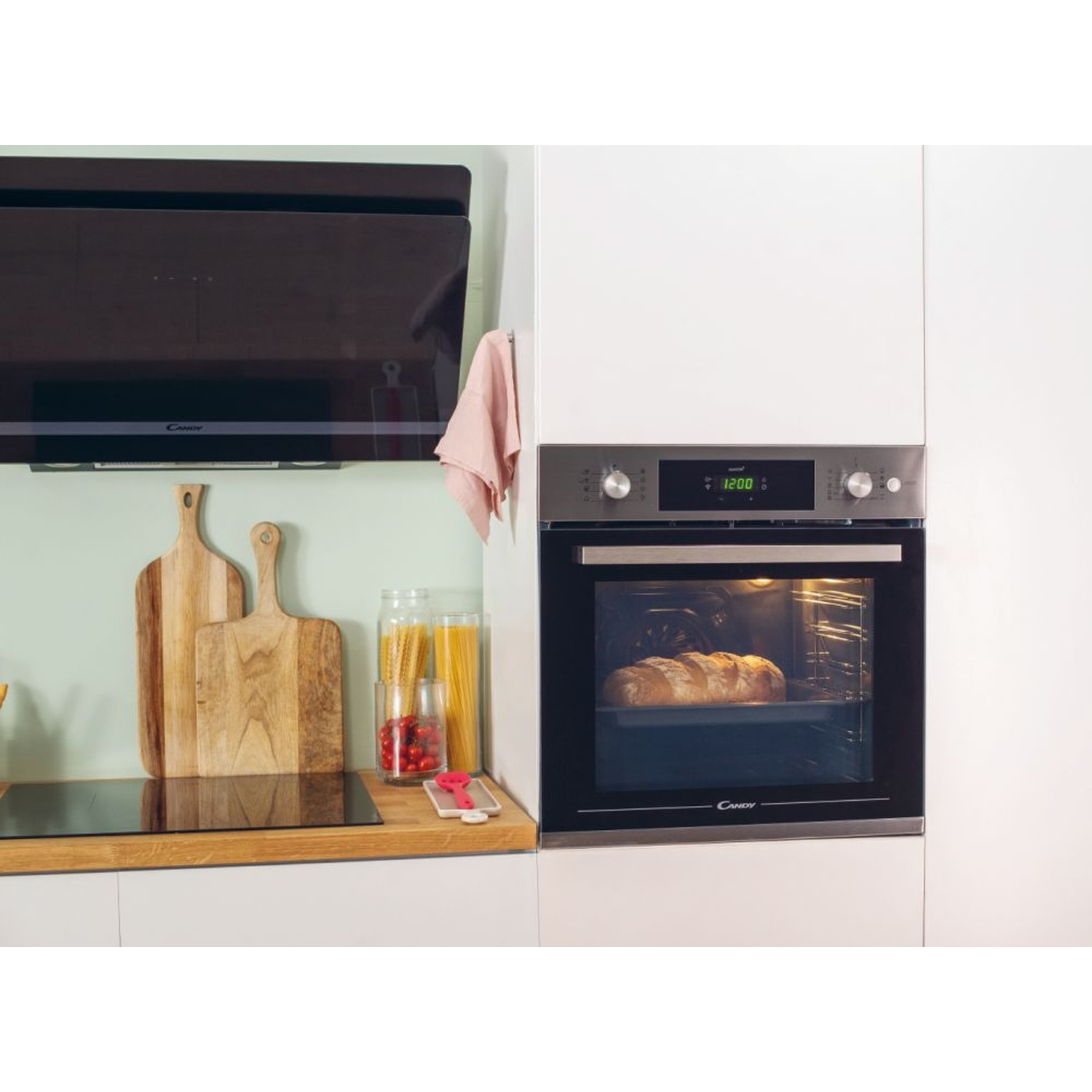 Una pagnotta cuoce in un forno moderno sopra un piano cottura con assi di legno.