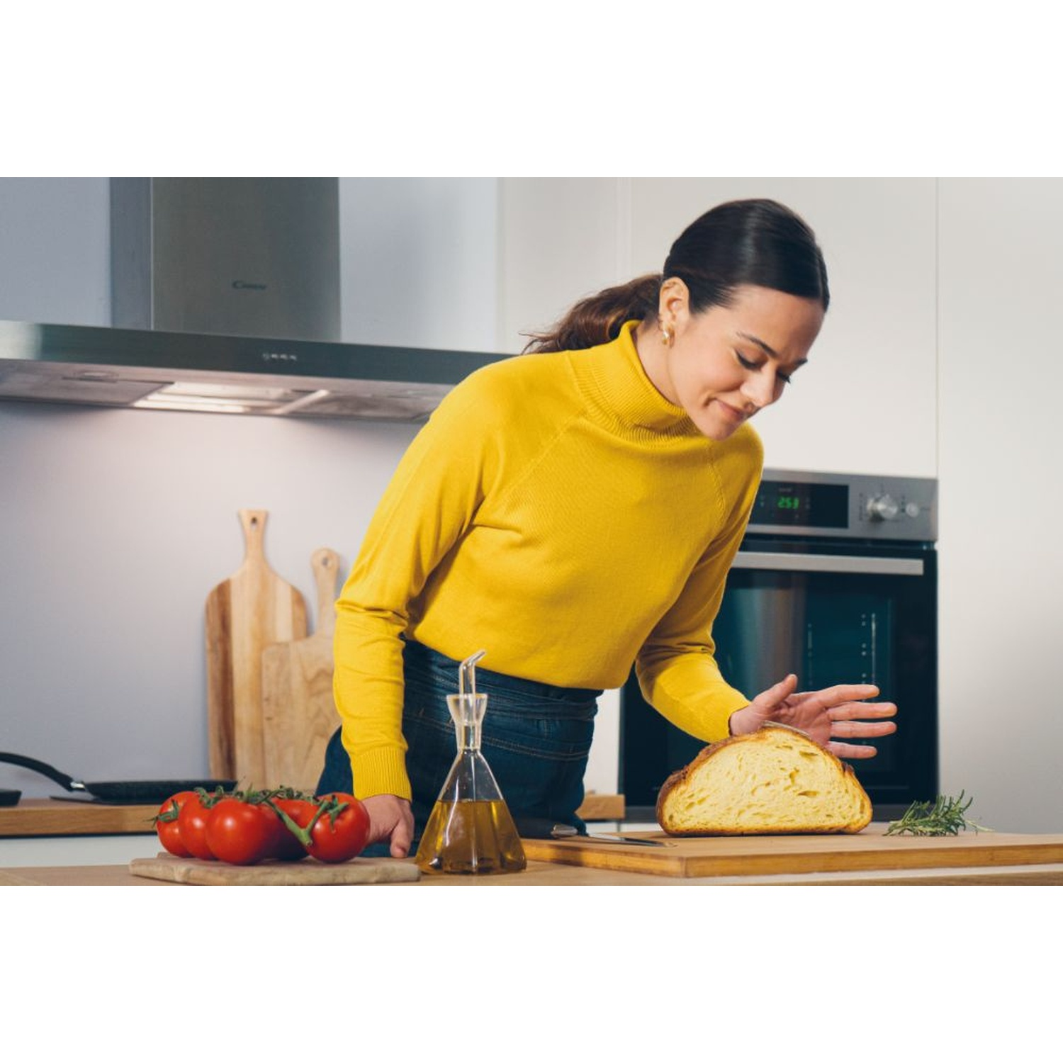 Una donna in maglione giallo taglia il pane in cucina.