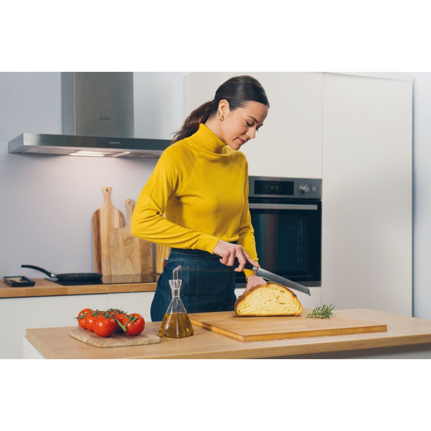 Donna affetta pane in cucina con pomodori e olio.