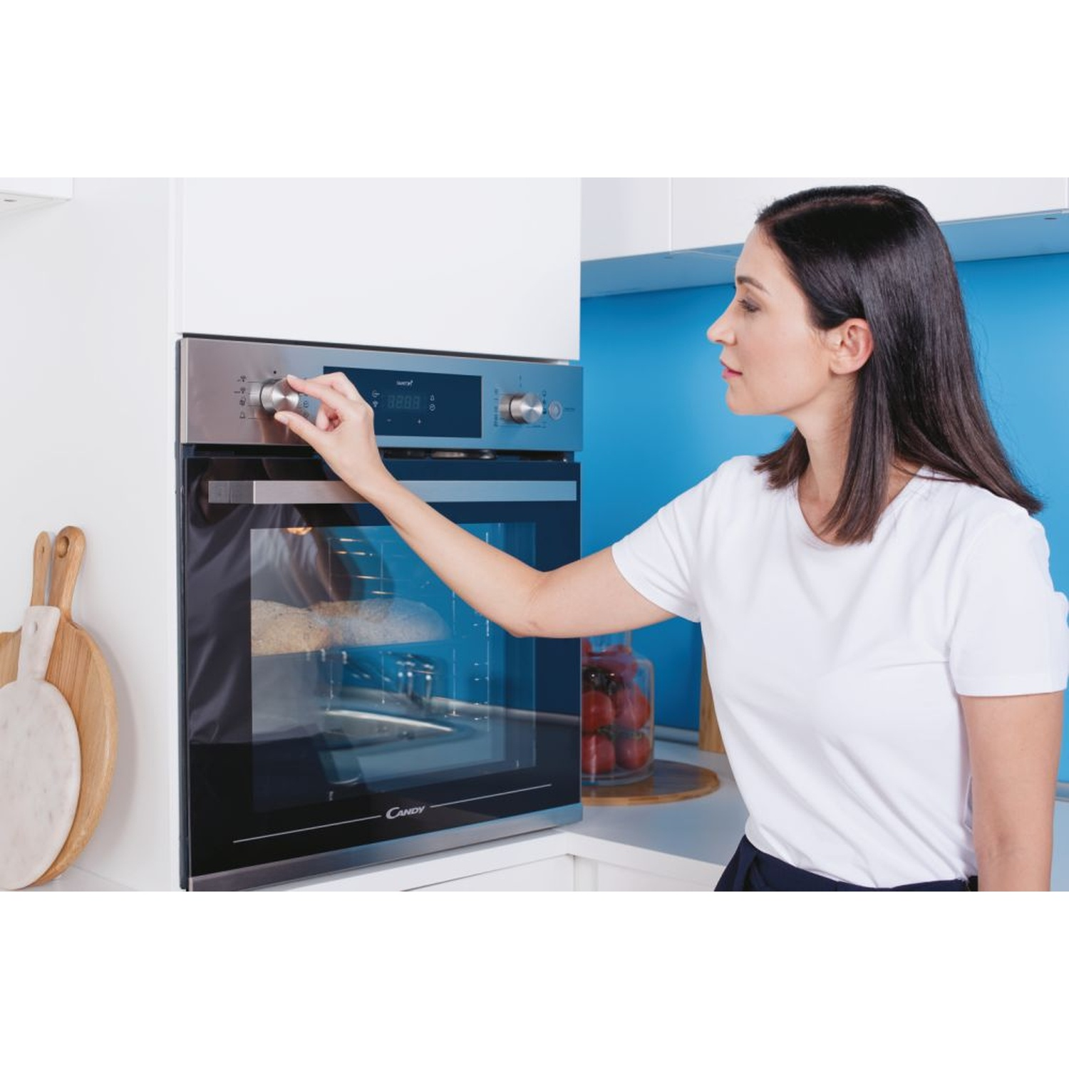 Una donna regola la manopola di un forno moderno mentre il pane cuoce all'interno.