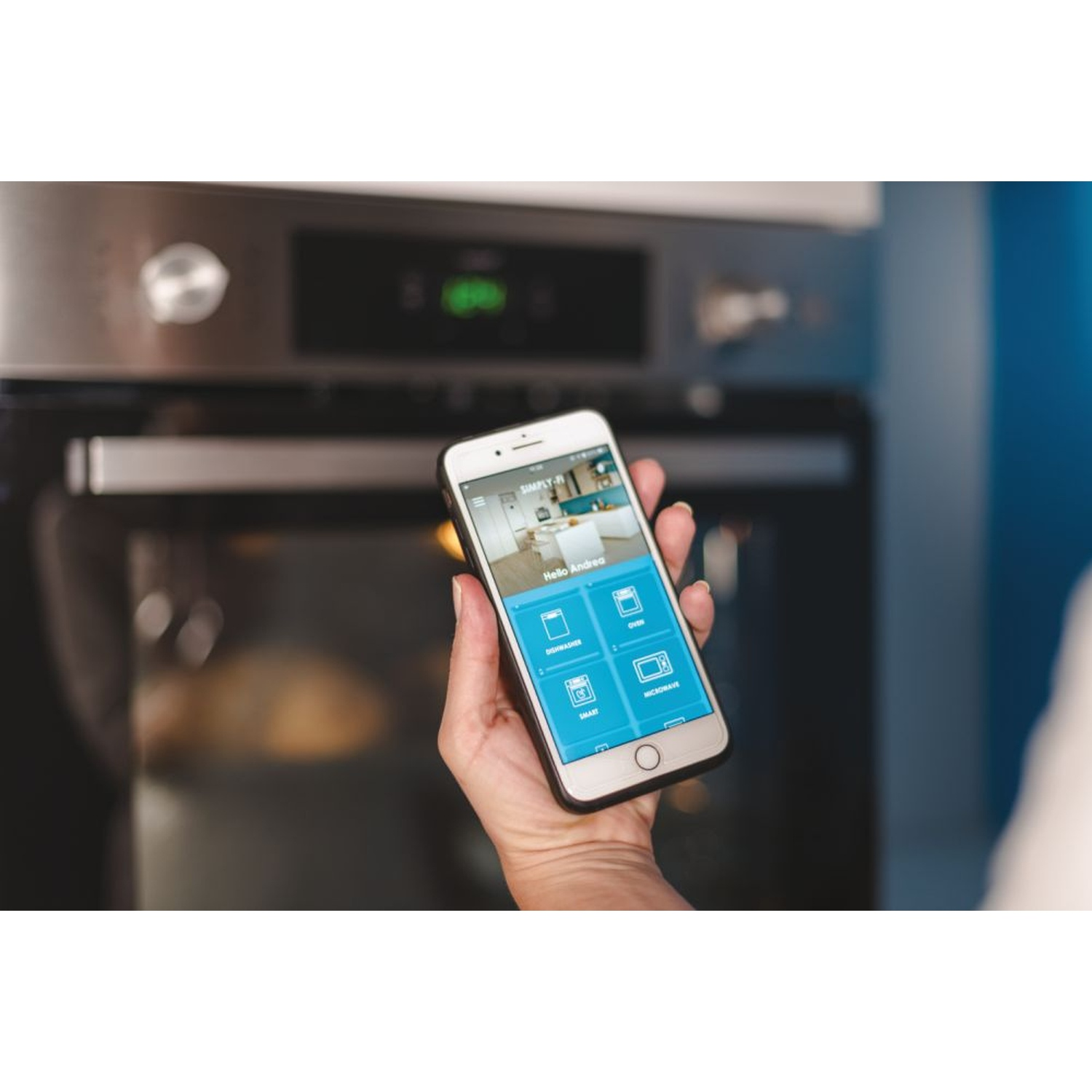 Una mano tiene uno smartphone davanti a un forno. L'app mostra elettrodomestici.