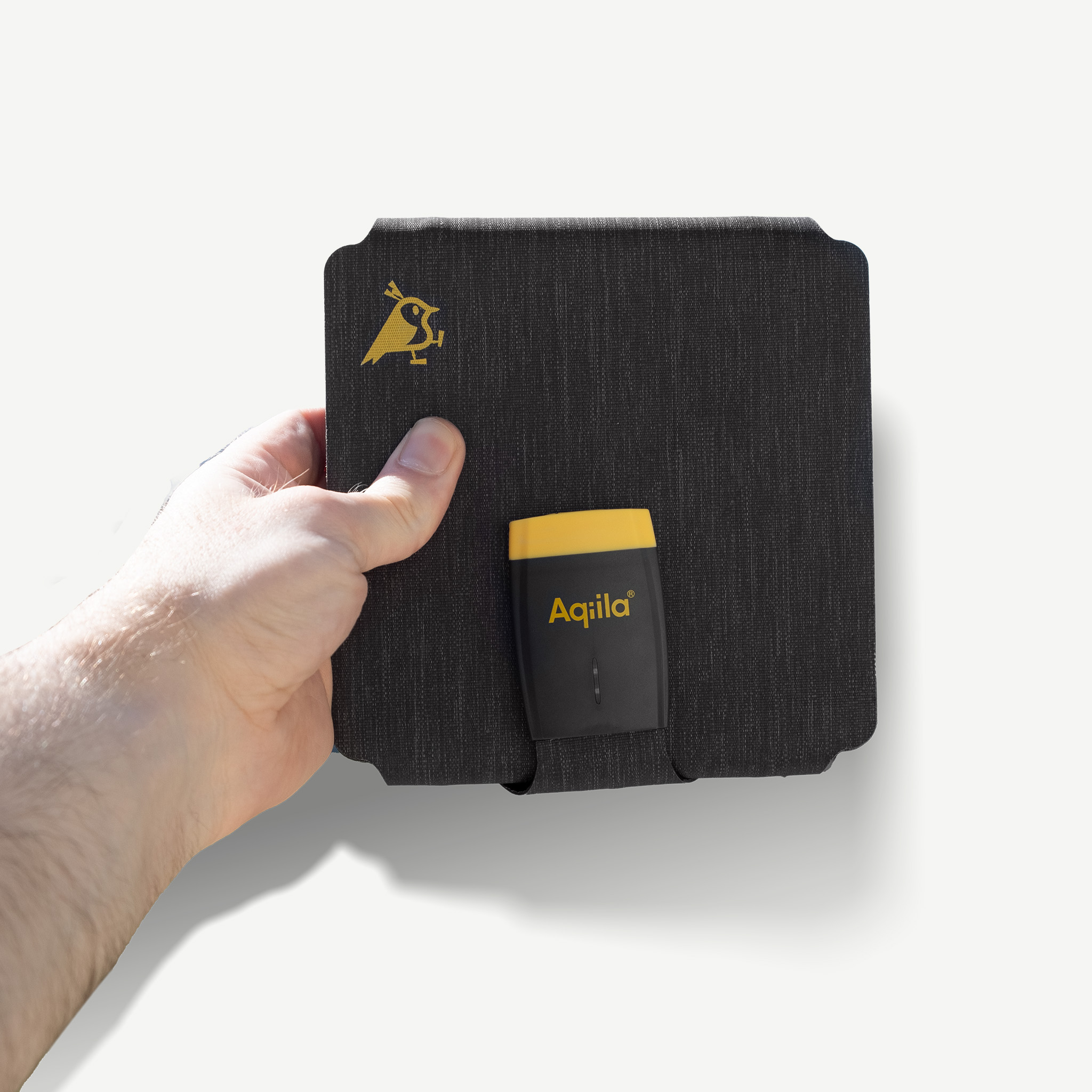 Eine Hand hält ein schwarzes Etui mit gelbem Logo. Ein gelber Stecker ist angebracht.