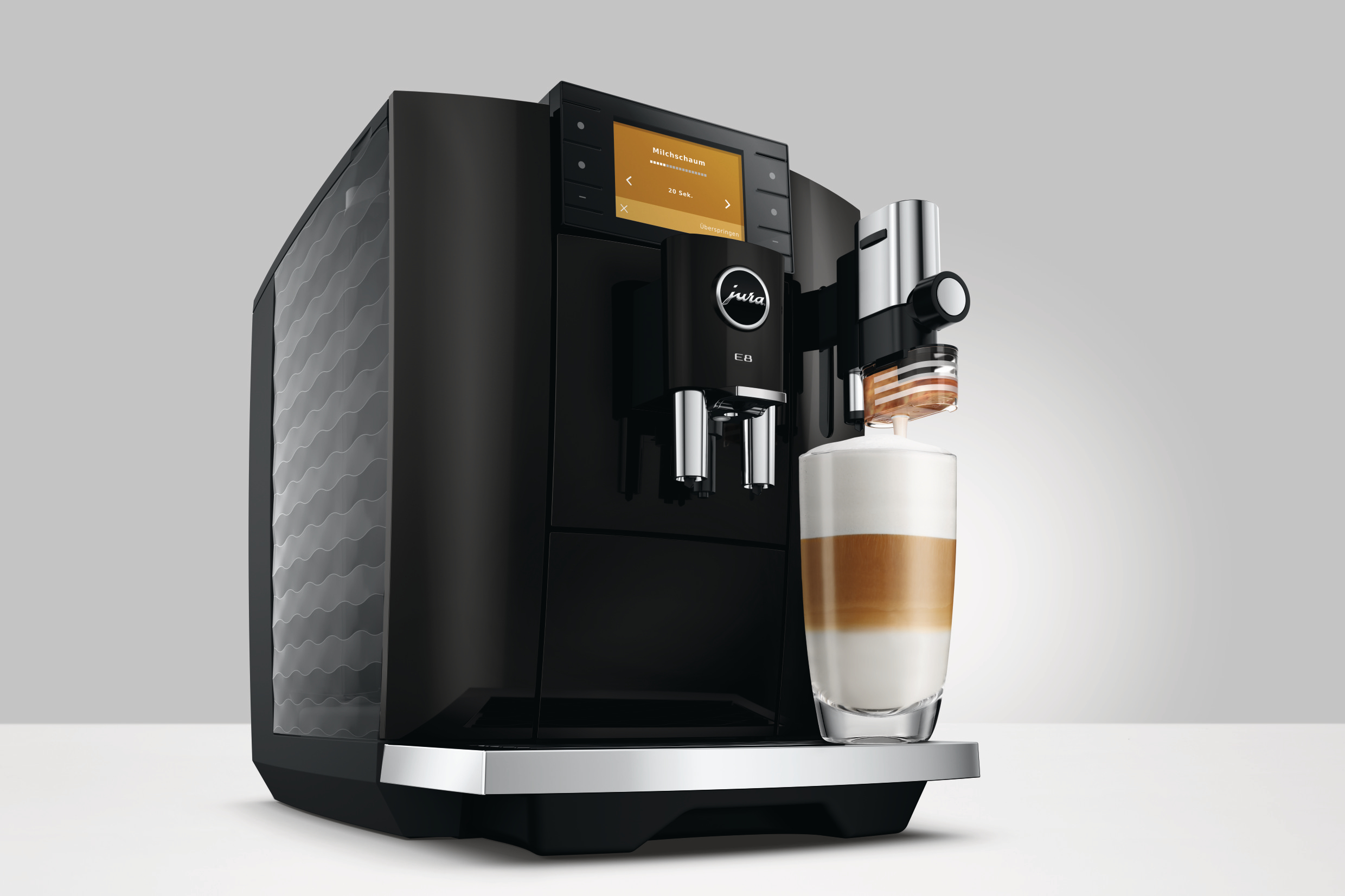 Schwarze Kaffeemaschine mit Milchgetränk in einem Glas.