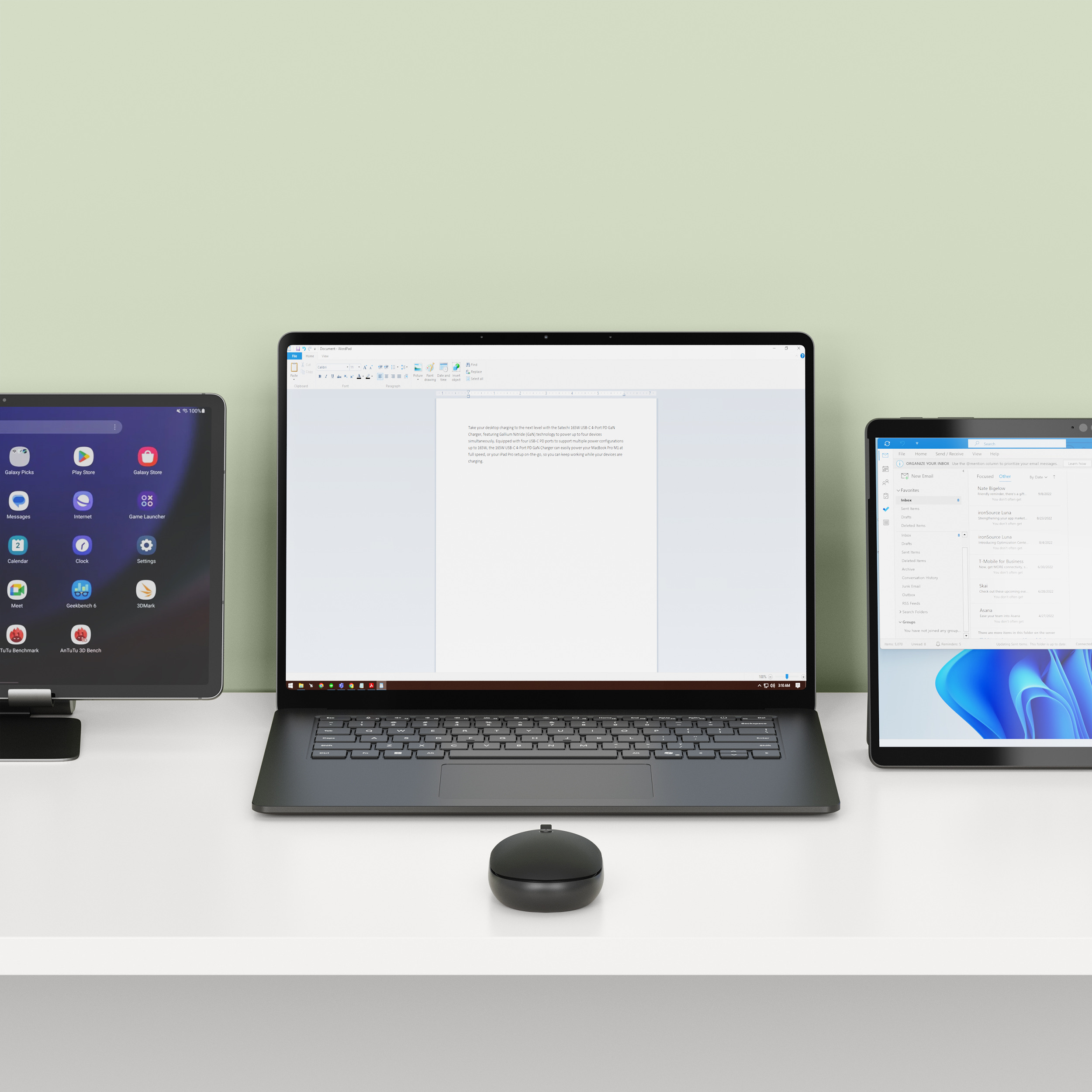 Un laptop con elaborazione testi aperta, affiancato da due tablet e un mouse.