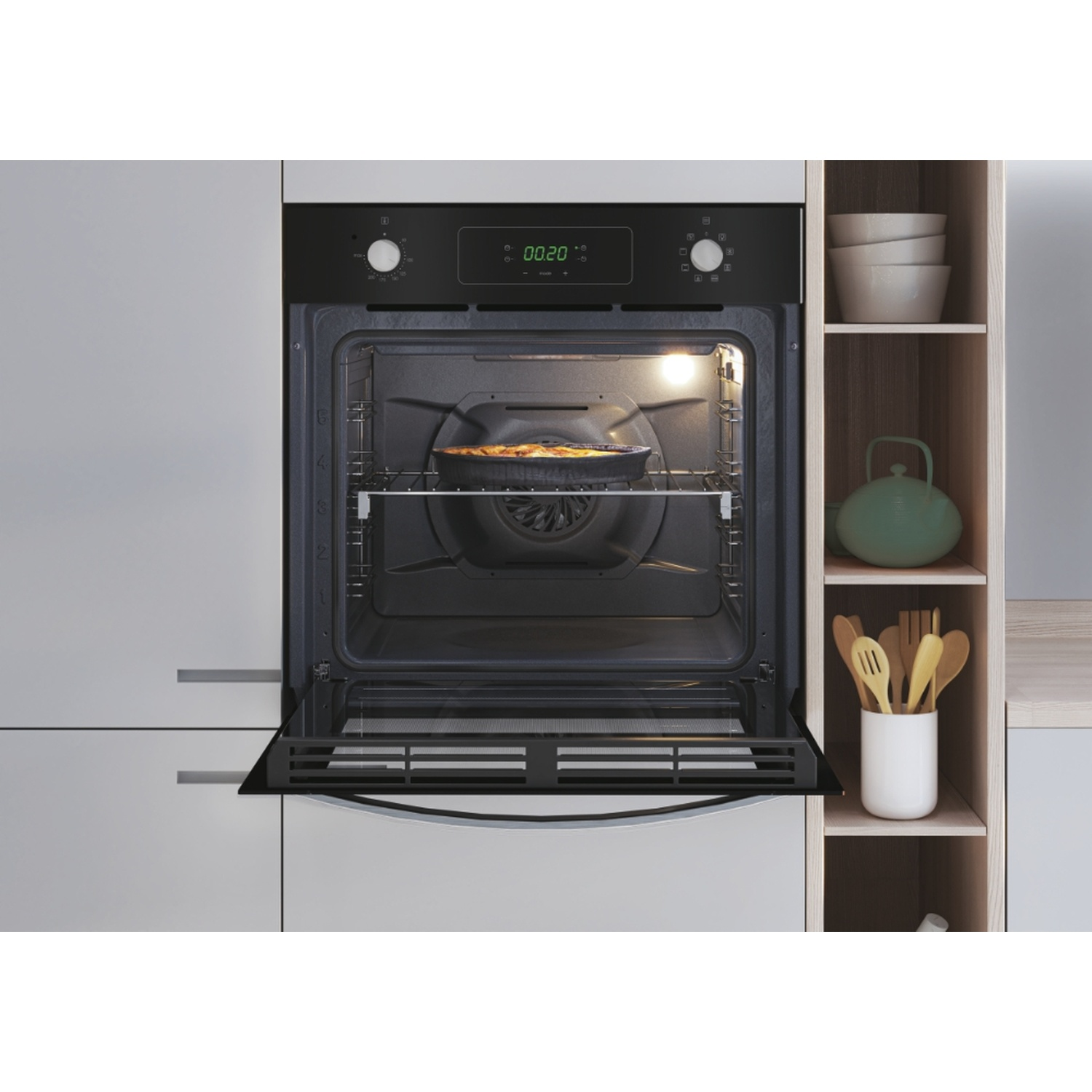 Un forno da incasso aperto con una torta all'interno. Accanto, una mensola con ciotole e utensili.