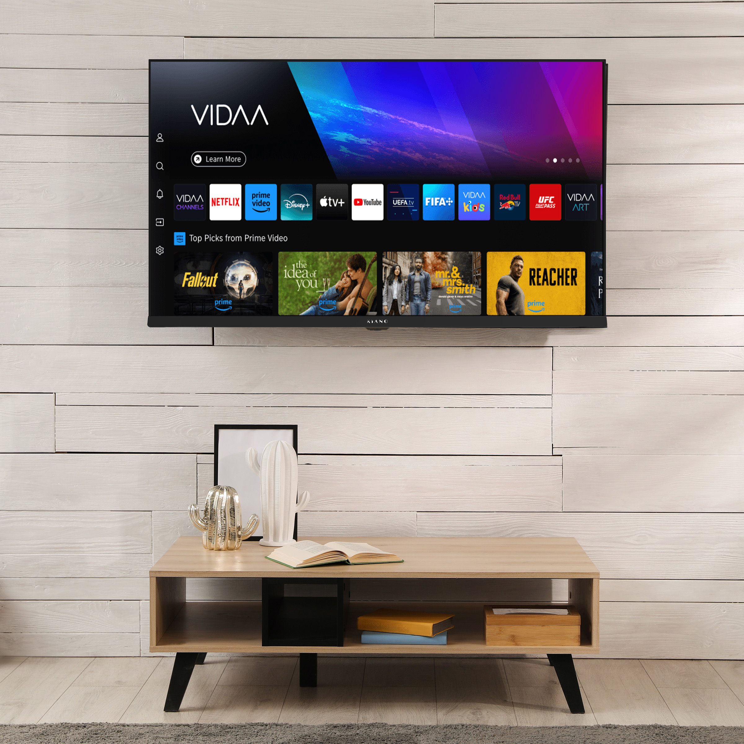 Nowoczesny telewizor z interfejsem smart wisi nad drewnianym stolikiem z dekoracjami.