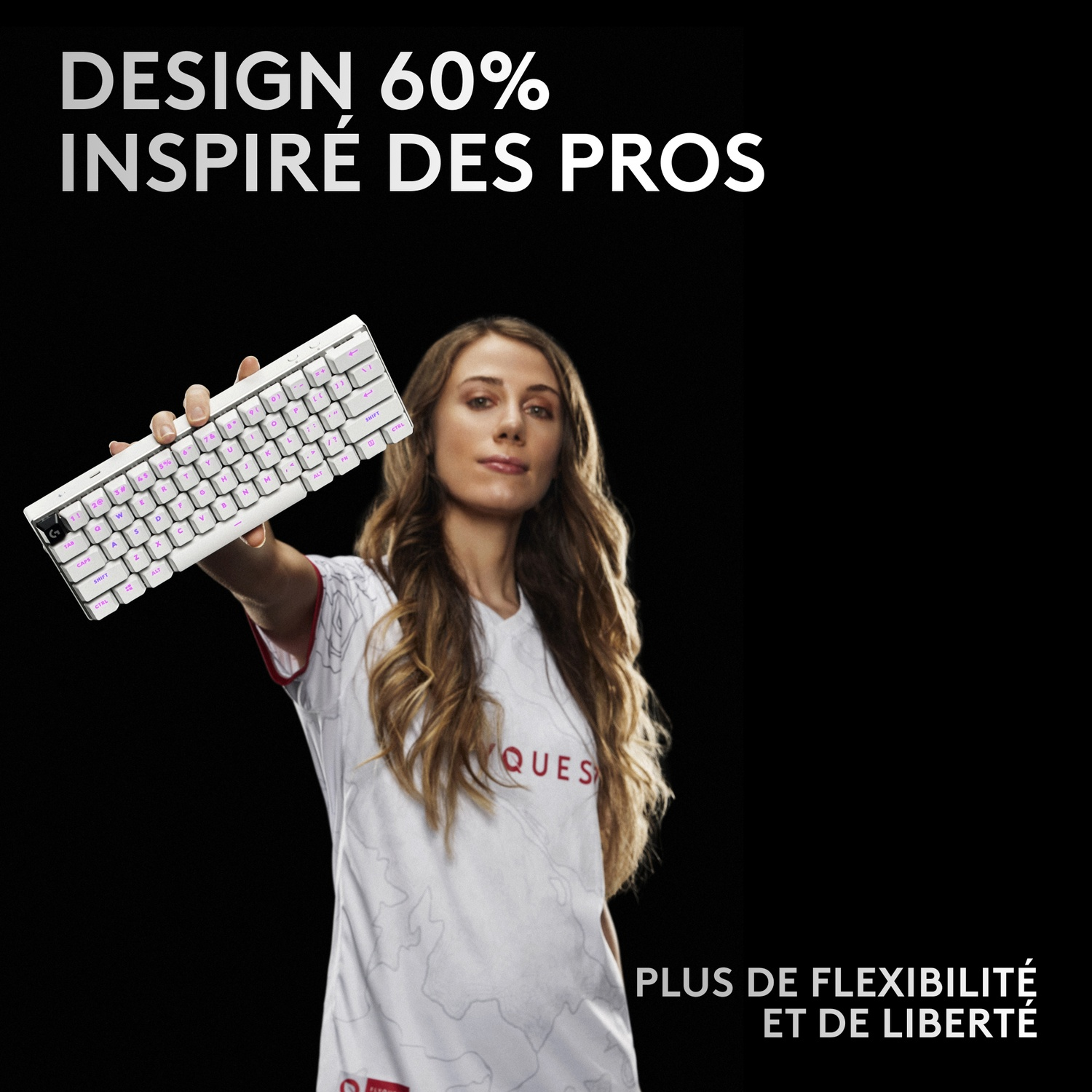 Une femme tient un clavier blanc rétroéclairé en rose sur fond noir.