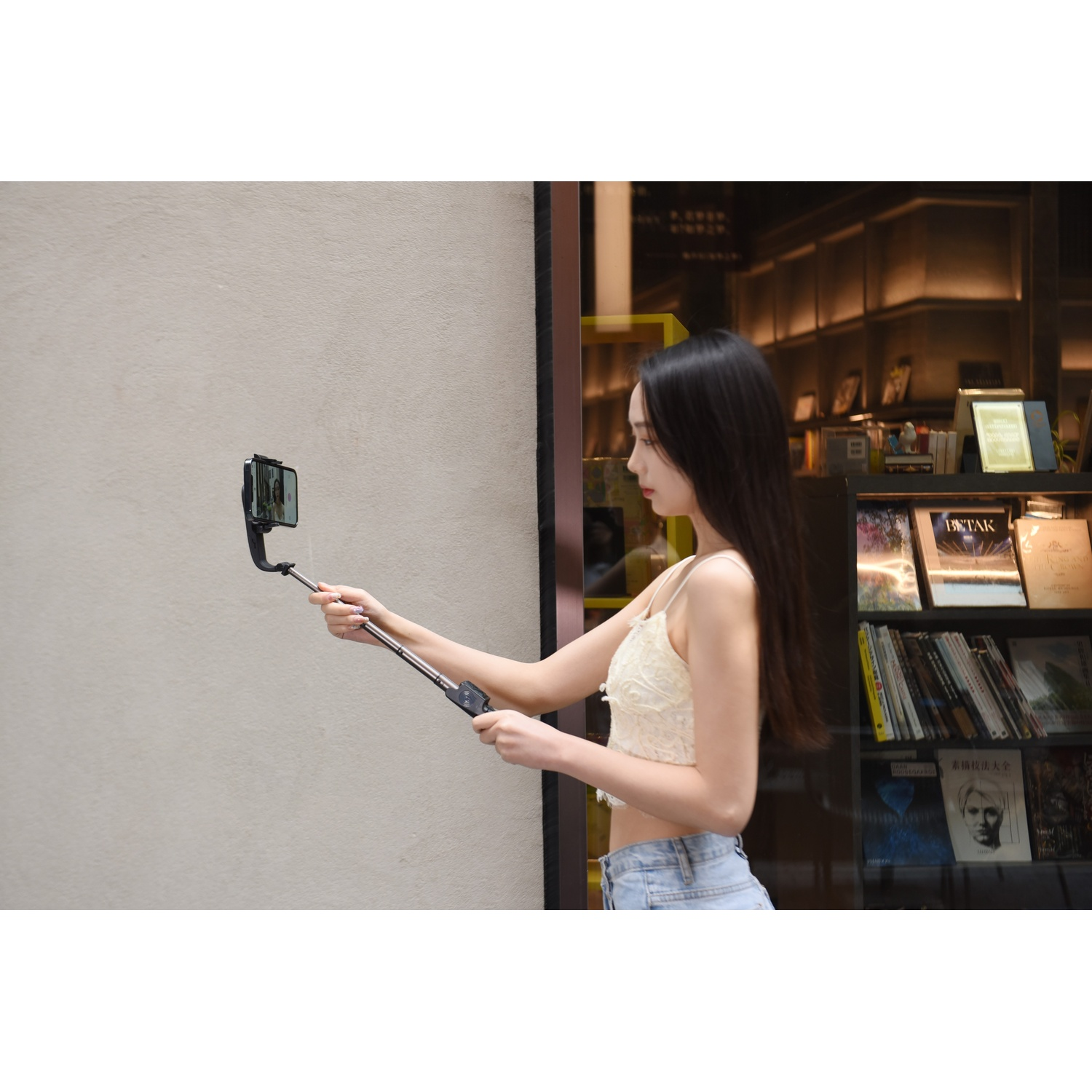 Una donna tiene un selfie stick estensibile con un telefono, filmandosi.