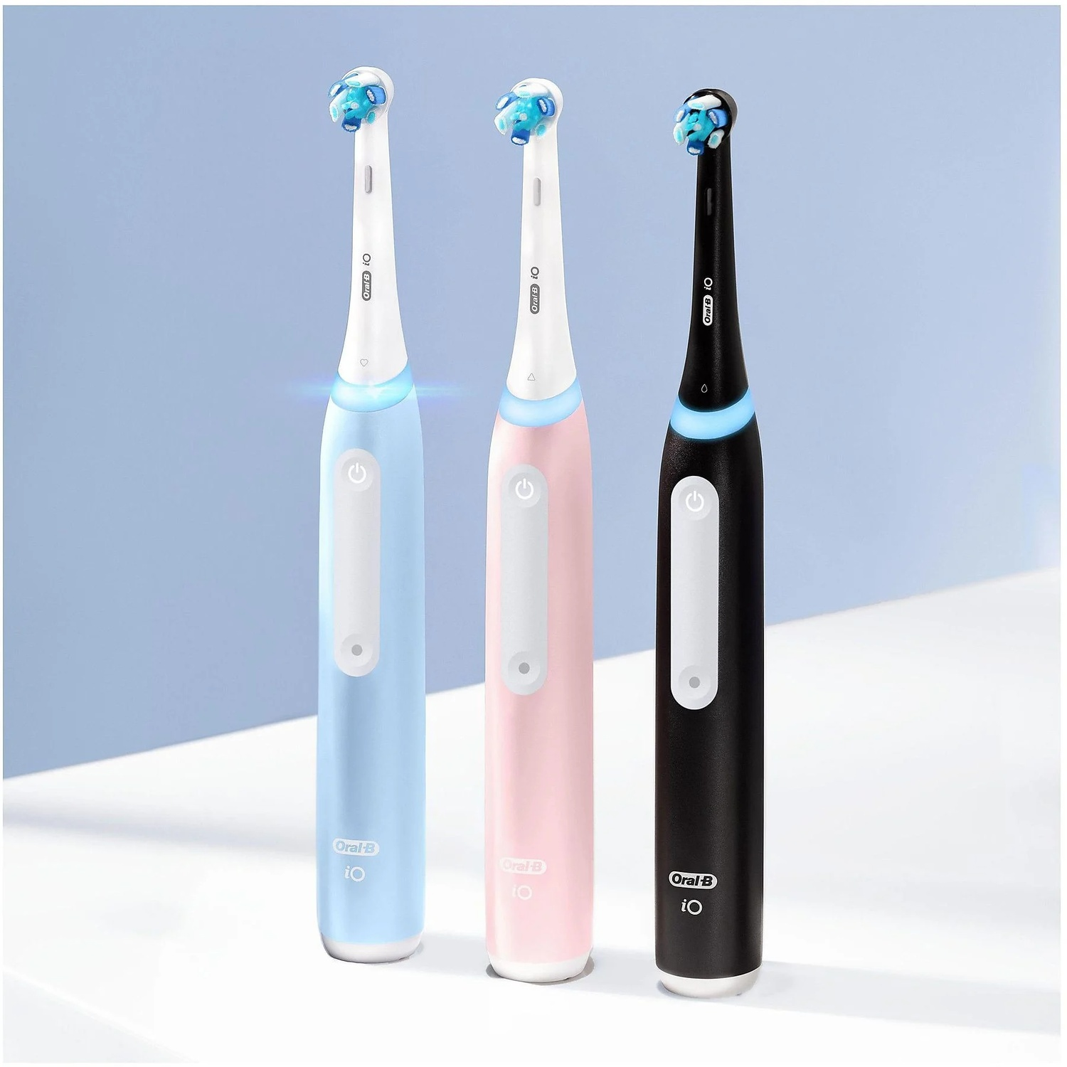 Trois brosses à dents électriques : bleue, rose et noire, avec des poils bleus.