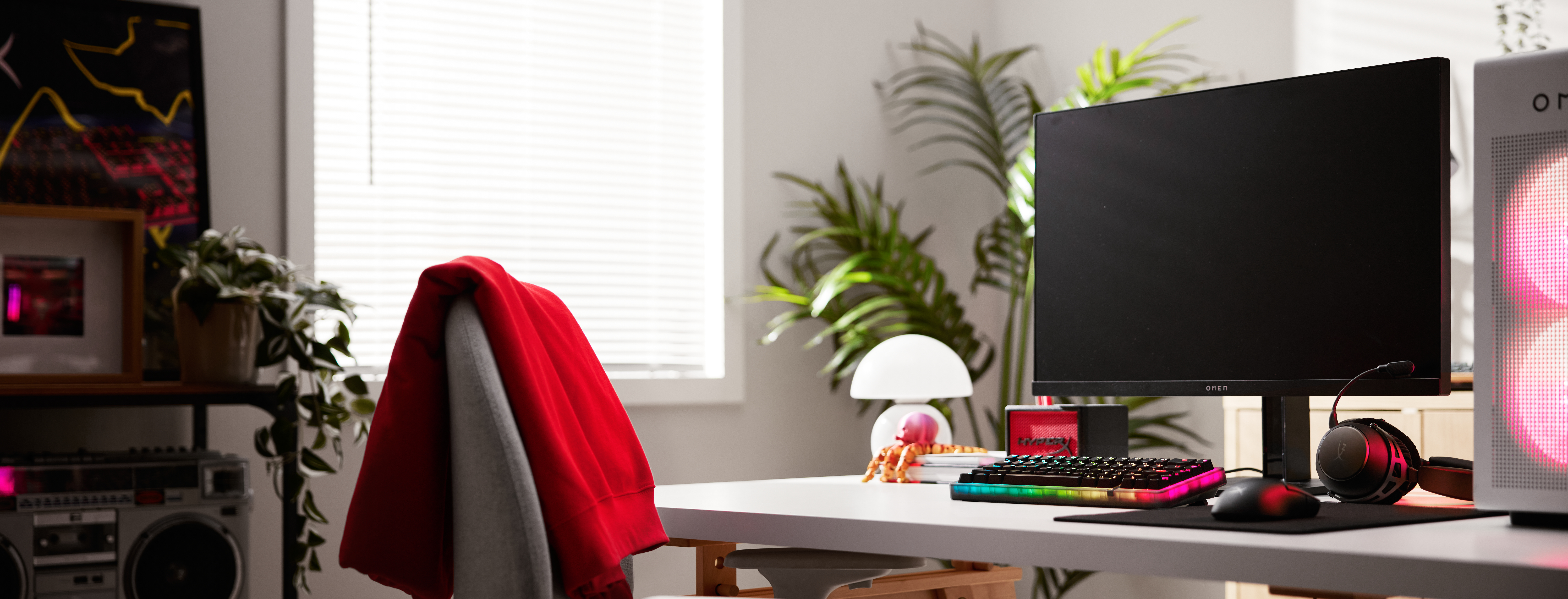 Een bureau met pc, toetsenbord, muis, koptelefoon en planten.