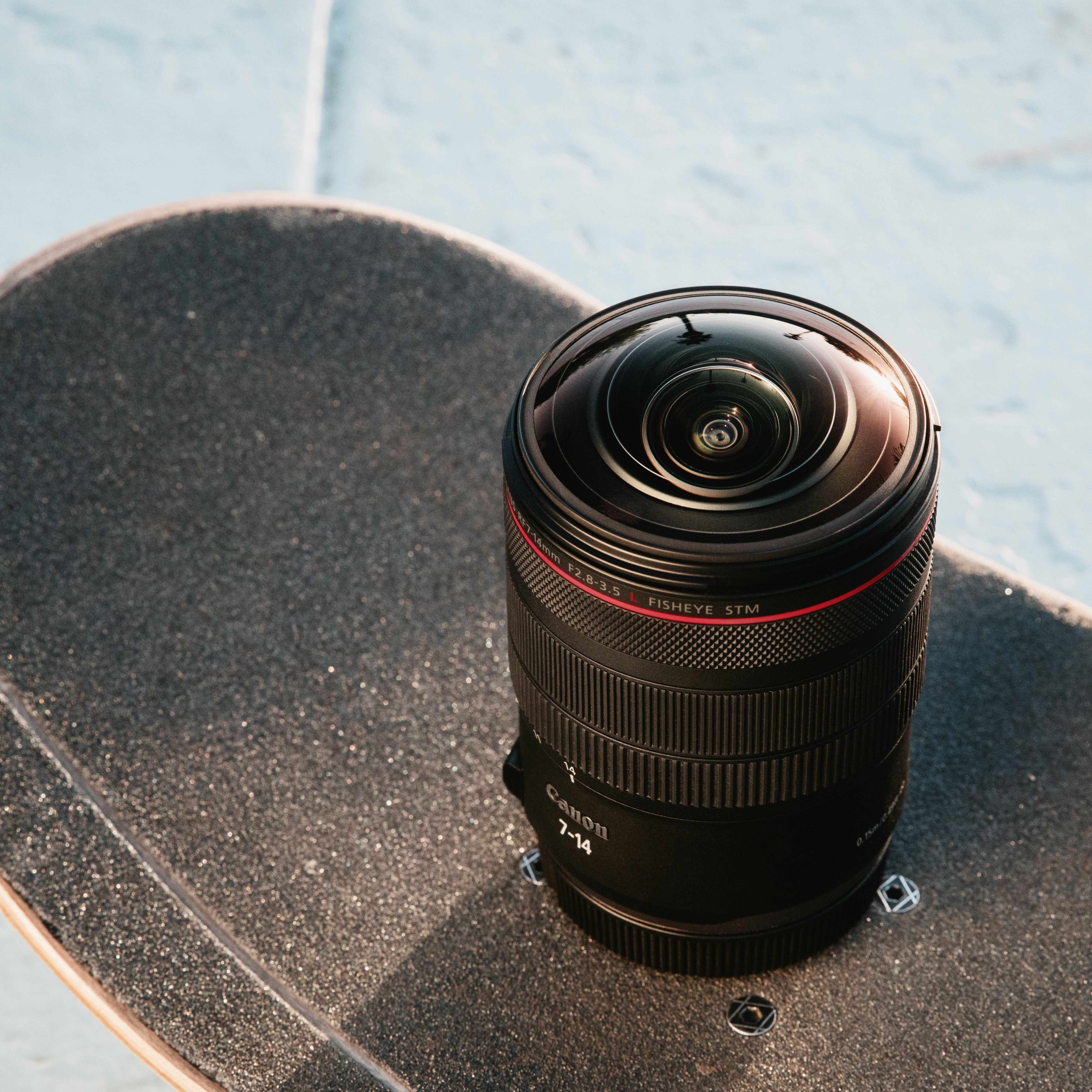Un objectif fisheye Canon repose sur un skateboard.