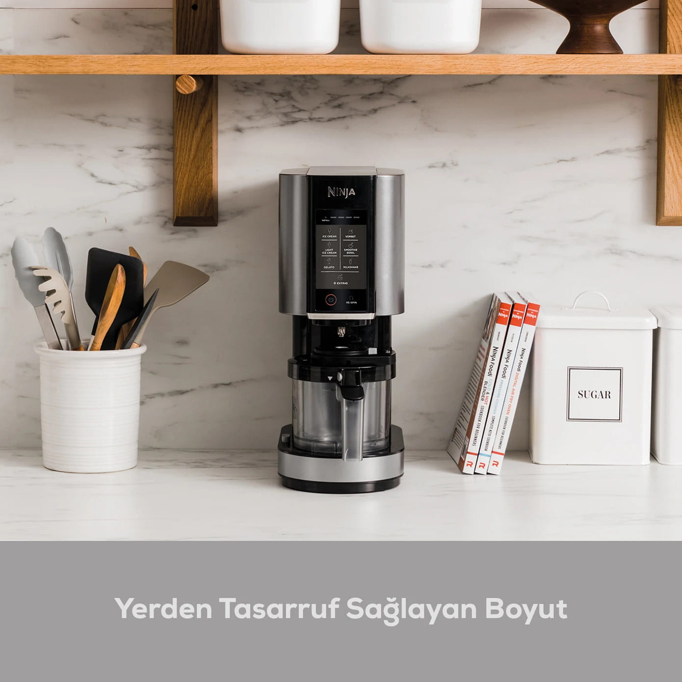 Ninja blender mutfak tezgahında, yemek kitapları ve şeker kutusu yanında.