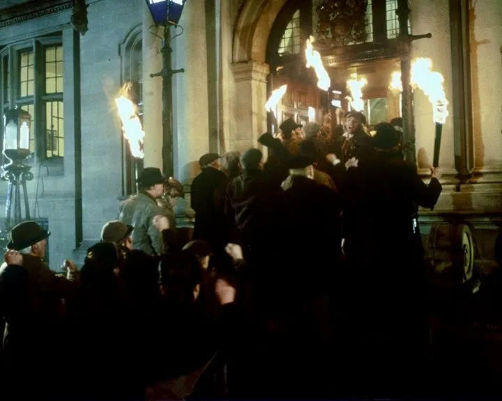 Eine Menge von Menschen mit Fackeln vor einem Gebäude bei Nacht.