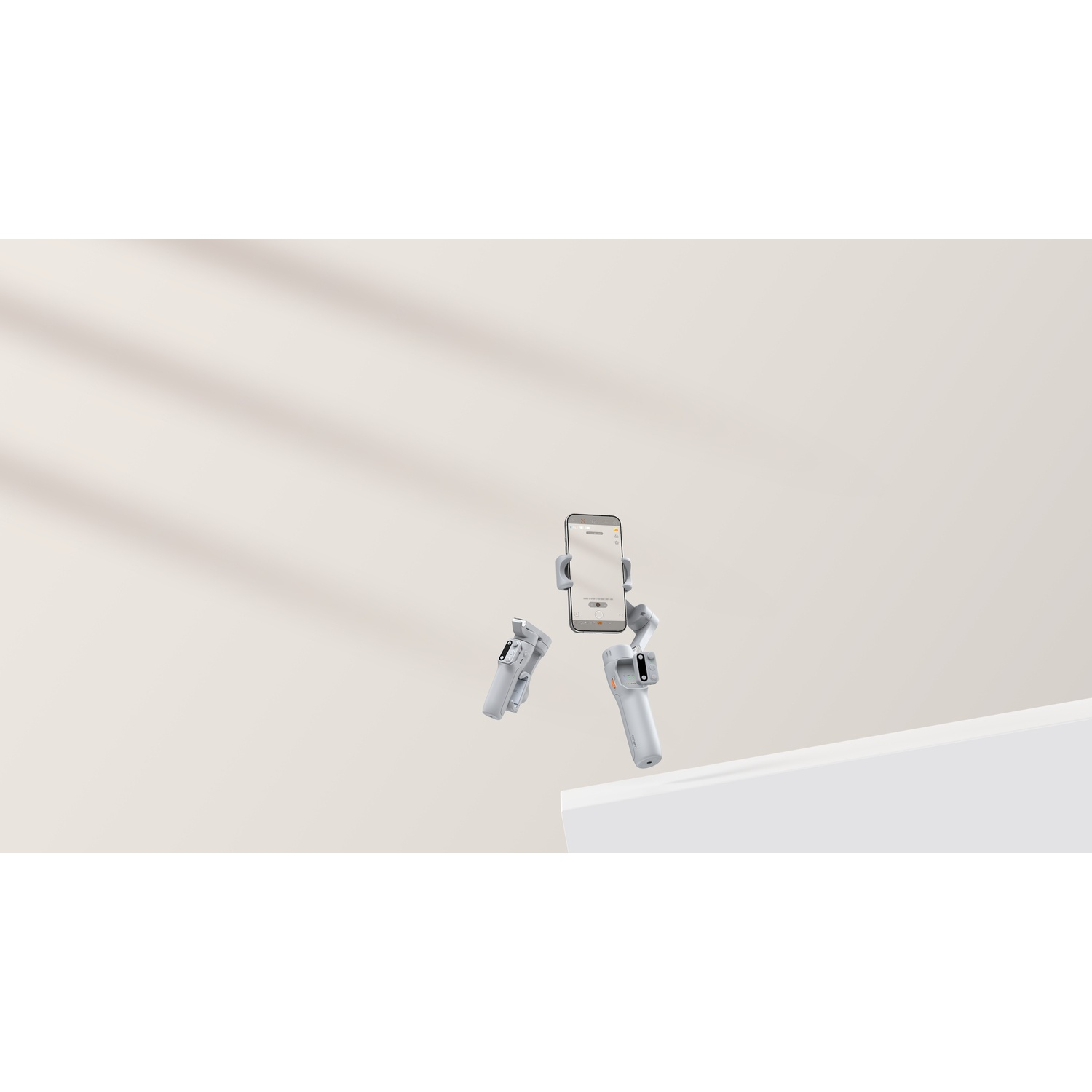 Un gimbal grigio con uno smartphone che galleggia su un piedistallo bianco.