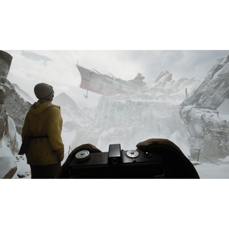 Osoba w żółtym ubraniu patrzy na ogromny statek osadzony na ośnieżonej górze.