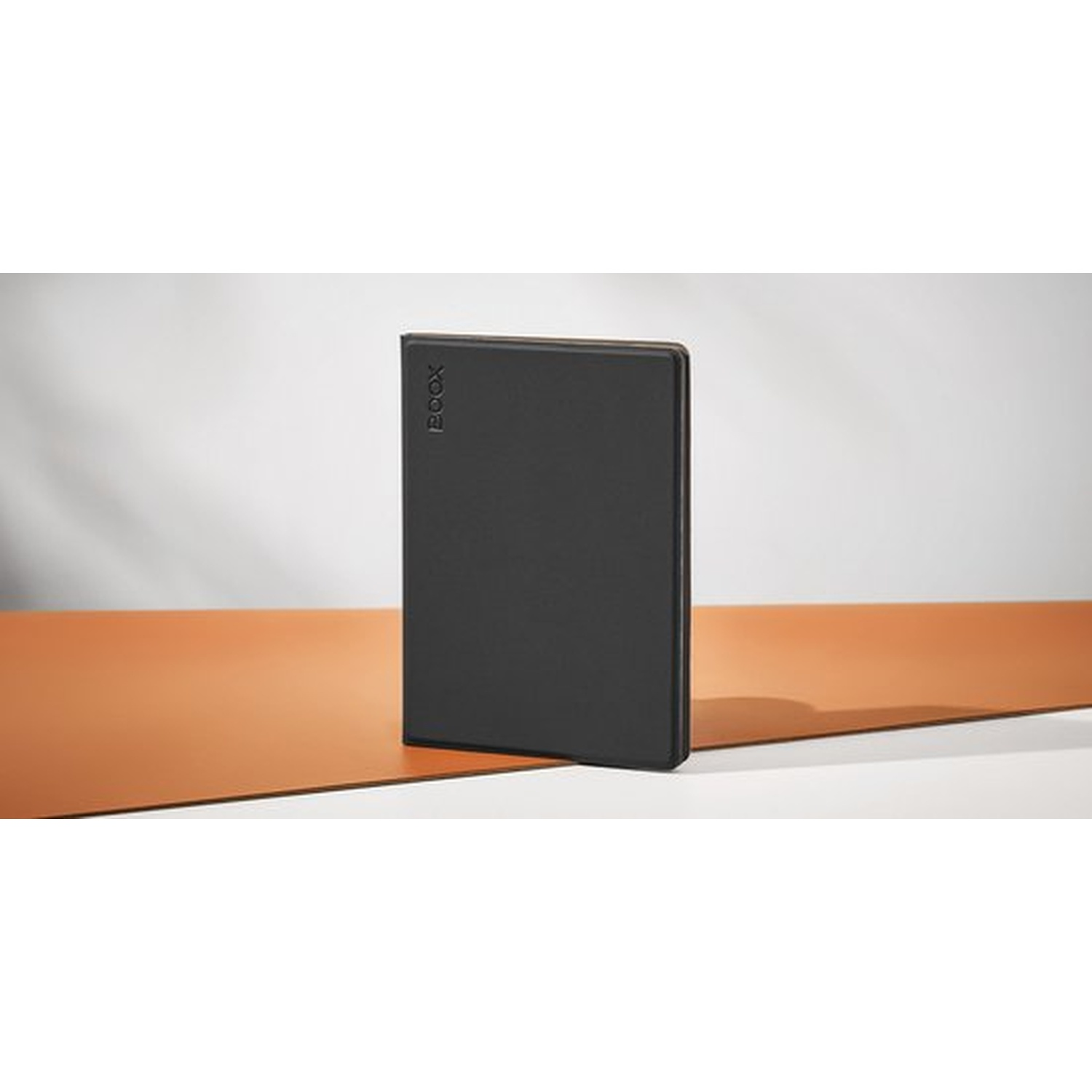 Een zwarte e-reader met BOOX-logo staat op een oranje en wit oppervlak.