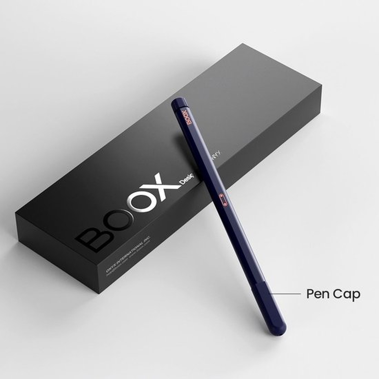 Un stylo bleu foncé repose à côté d'une boîte noire étiquetée "BOOX".
