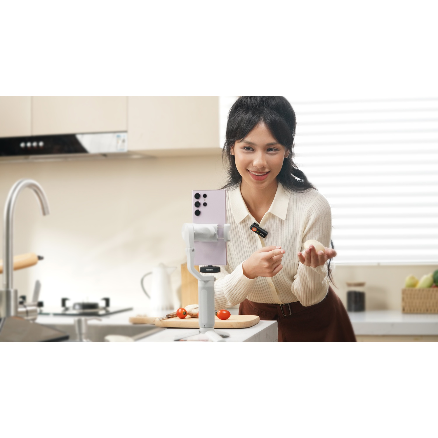Una donna si filma mentre cucina in una cucina con un telefono su un gimbal.