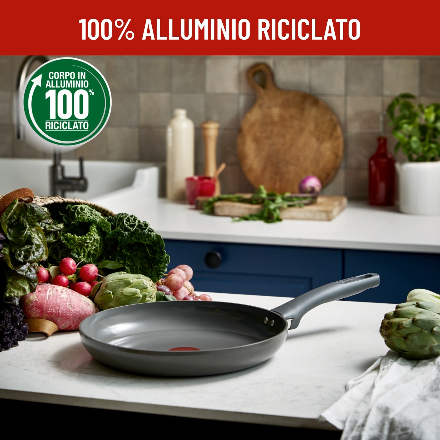 Padella grigia con verdure e uva su piano di lavoro in marmo. Alluminio 100% riciclato.