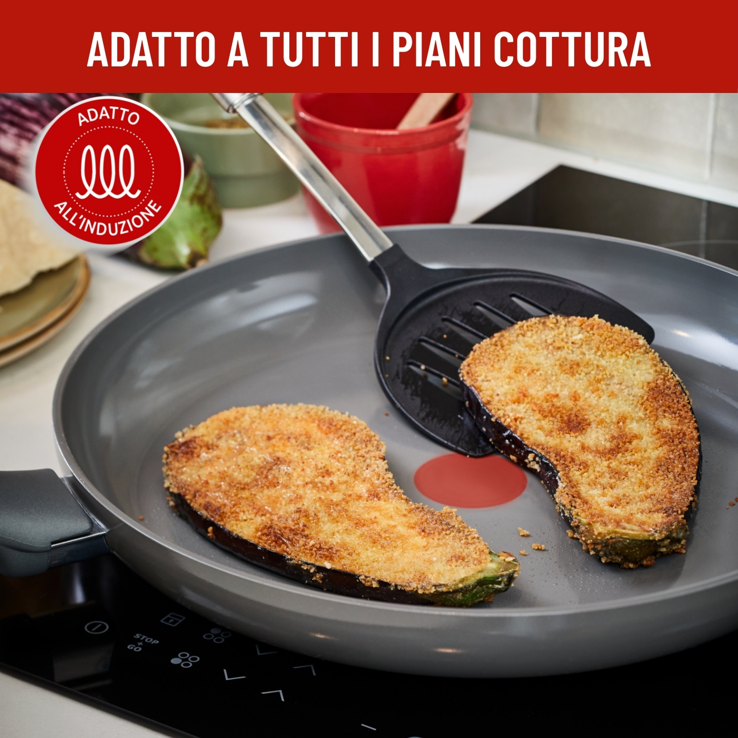 Fette di melanzane impanate friggono in padella su piano cottura a induzione.