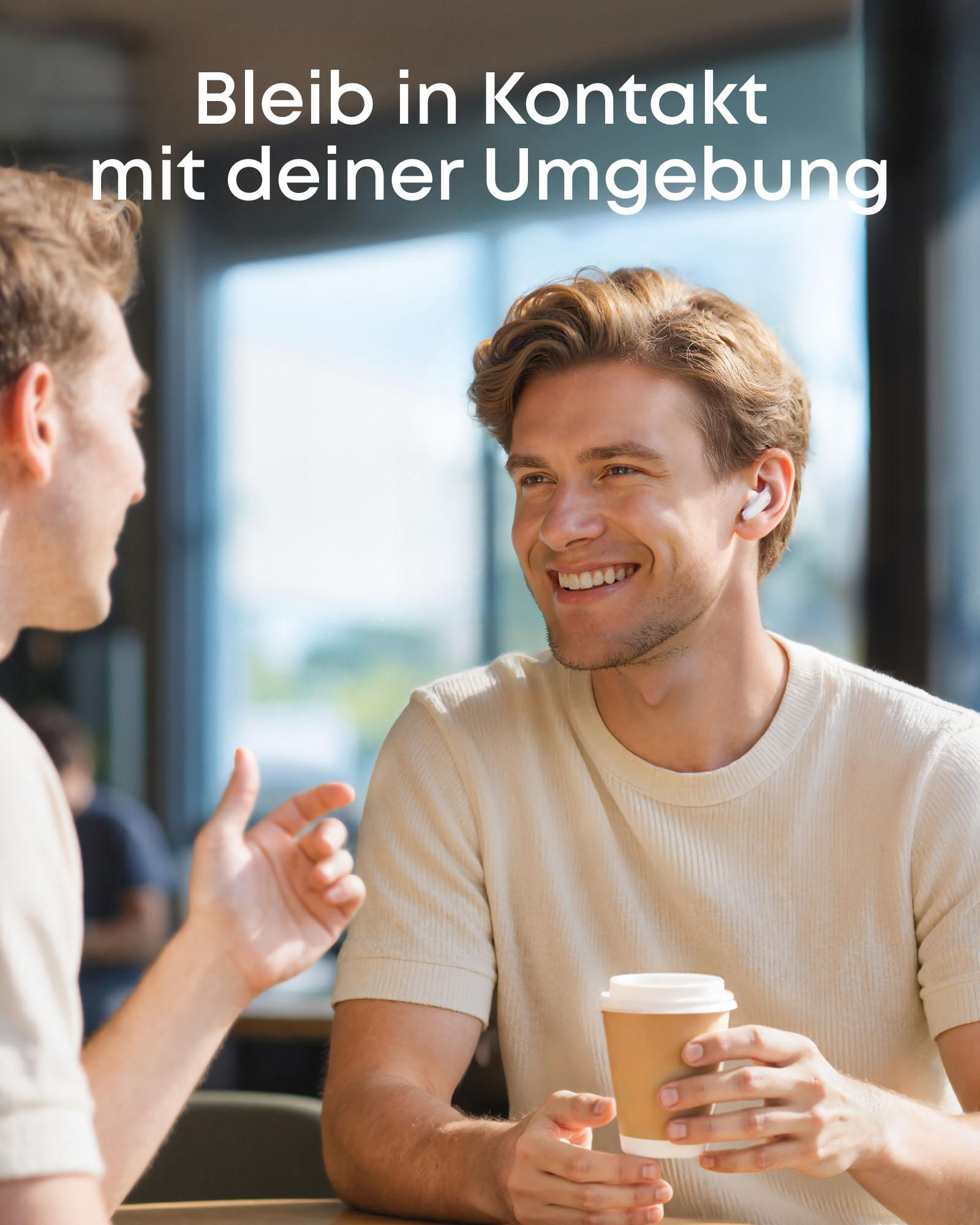 Zwei Männer unterhalten sich in einem Café, einer trinkt Kaffee und trägt Ohrhörer.