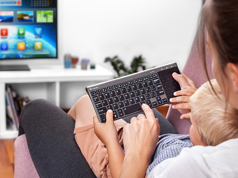 Kobieta i dziecko używają klawiatury przed telewizorem.