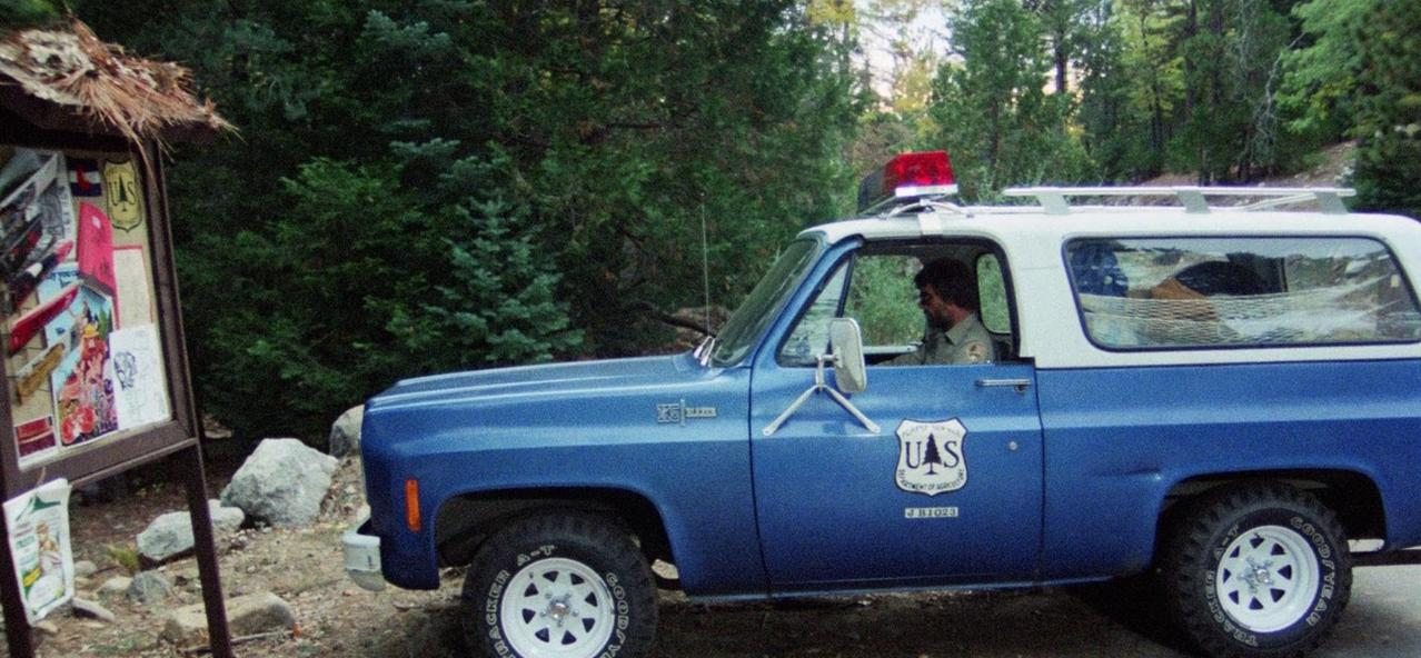 Ein Mann in Uniform fährt einen blauen Geländewagen mit rotem Blaulicht.