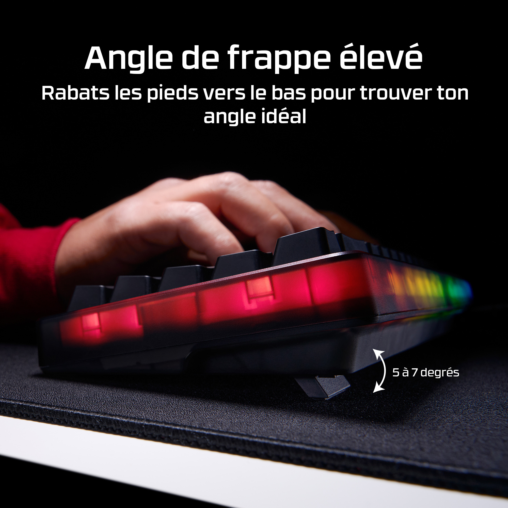 Une main tape sur un clavier avec éclairage RVB rouge et coloré.
