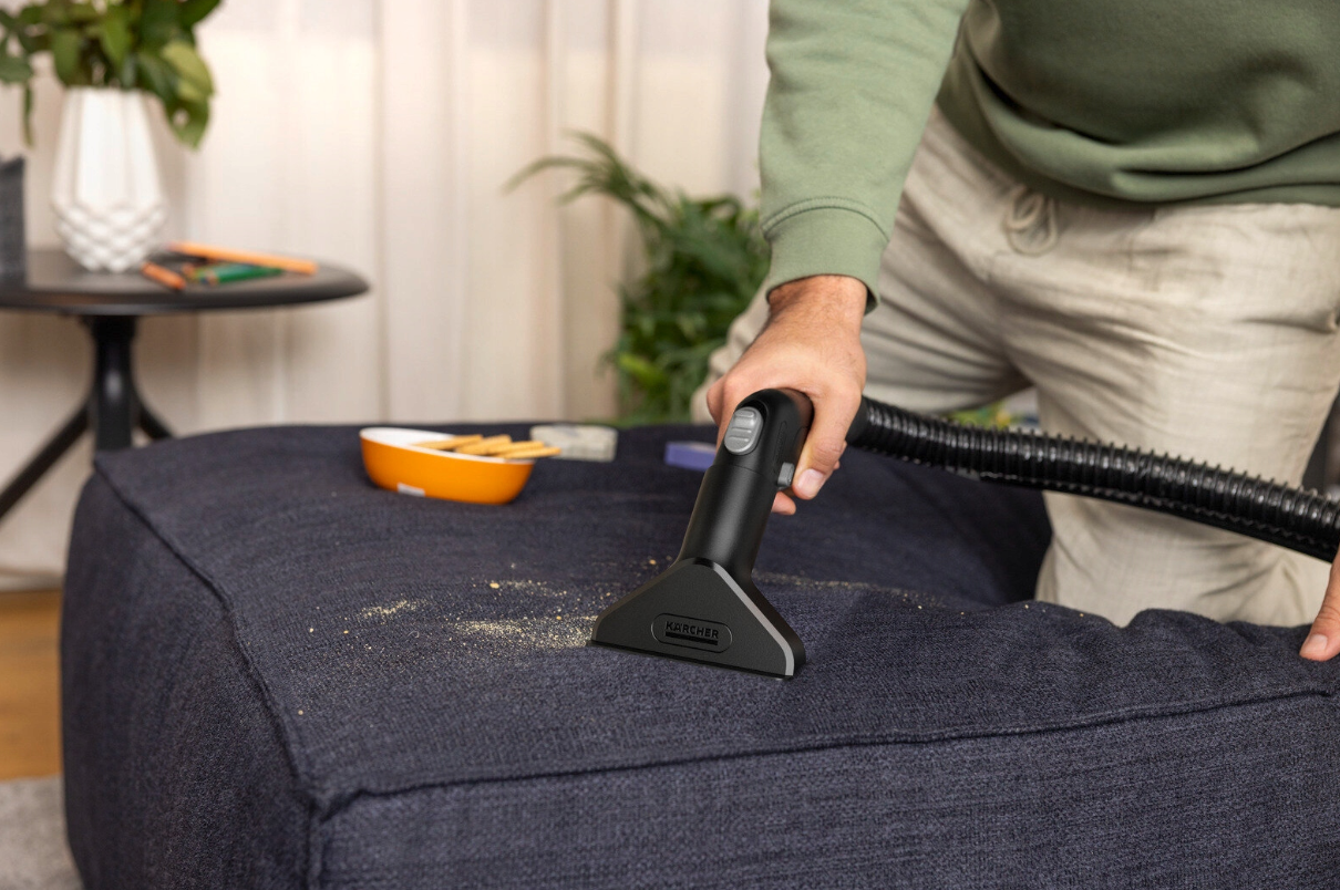 Osoba odkurza tapicerkę nasadką Kärcher.